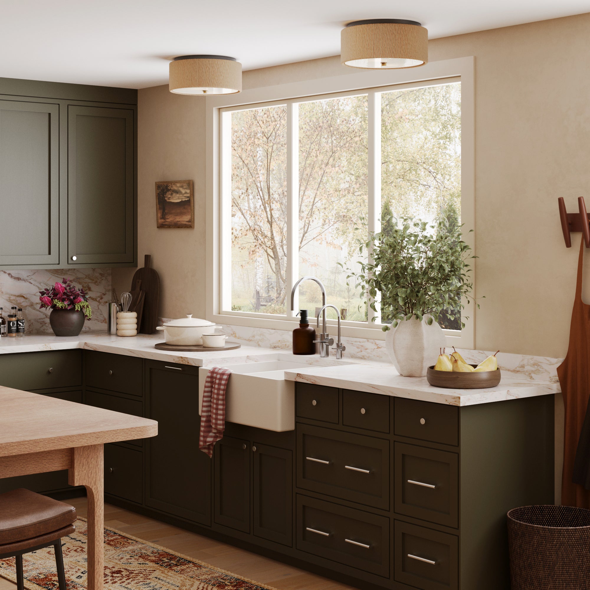 A cozy kitchen features dark green cabinets, a white farmhouse sink, marble countertops, and a large window with tree views. The decor is enhanced by Nathan James Seagrass Shade Flush Mount Ceiling Lights (Set of 2).