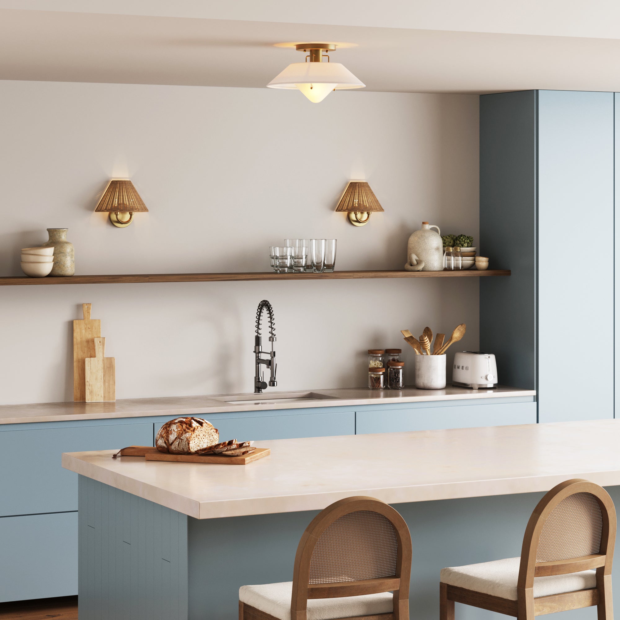 A modern kitchen with light blue cabinets, wood shelving with dishes, a tall-faucet sink, cutting boards, toaster, and bread on a light island with chairs beneath the Nathan James Linen Mid-Century Modern Flush Mount Ceiling Light.