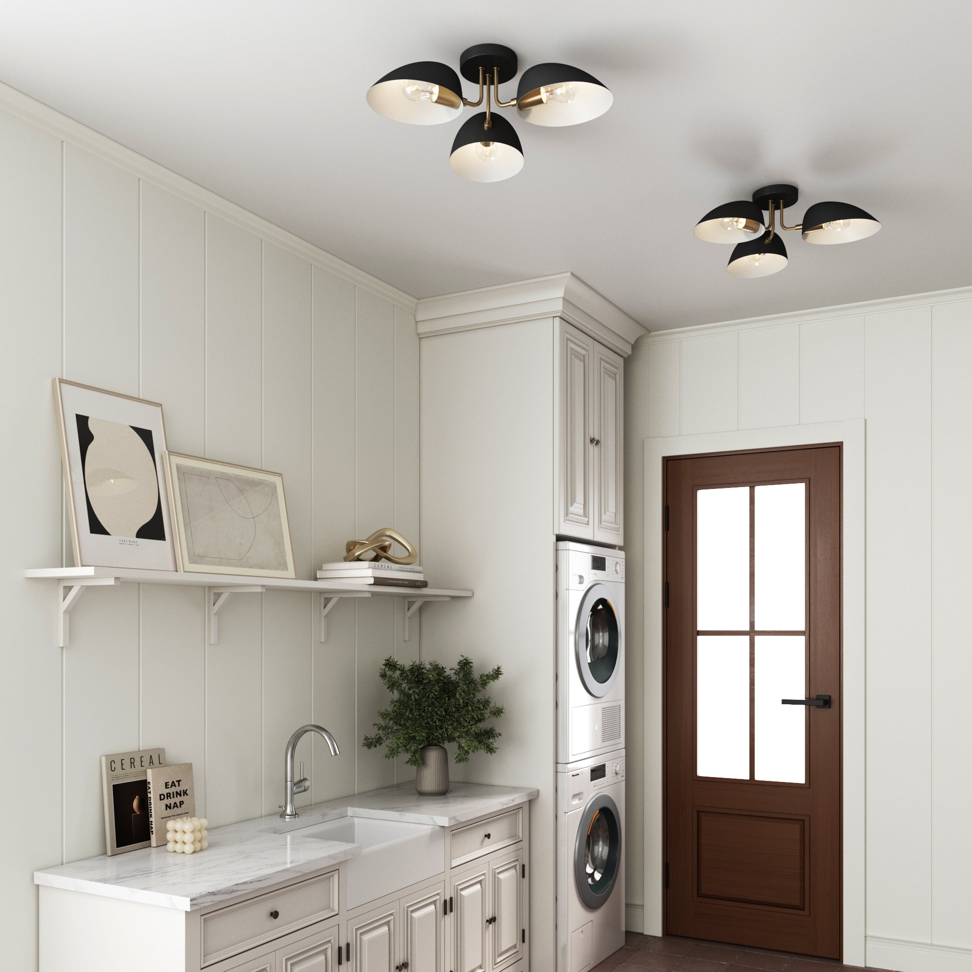 A modern laundry room featuring a built-in washer and dryer, sink, white cabinets, brown door with window, two Nathan James Metal 3-Arm Flush Mount Ceiling Lights (black), shelf with decor, and a small potted plant on the counter.