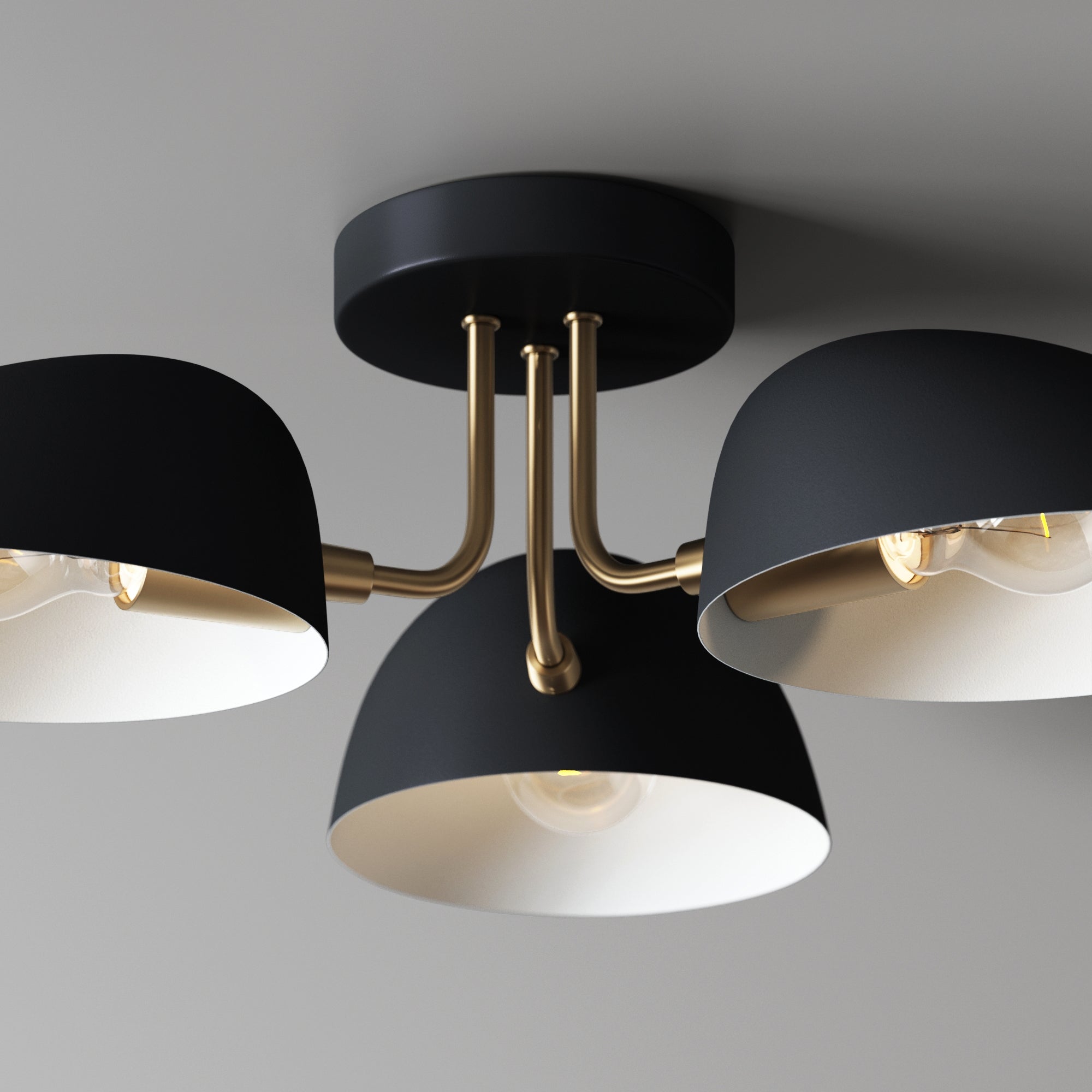 Modern ceiling light fixture with three black shade lamps, gold-colored arms, and exposed bulbs, mounted on a gray ceiling.