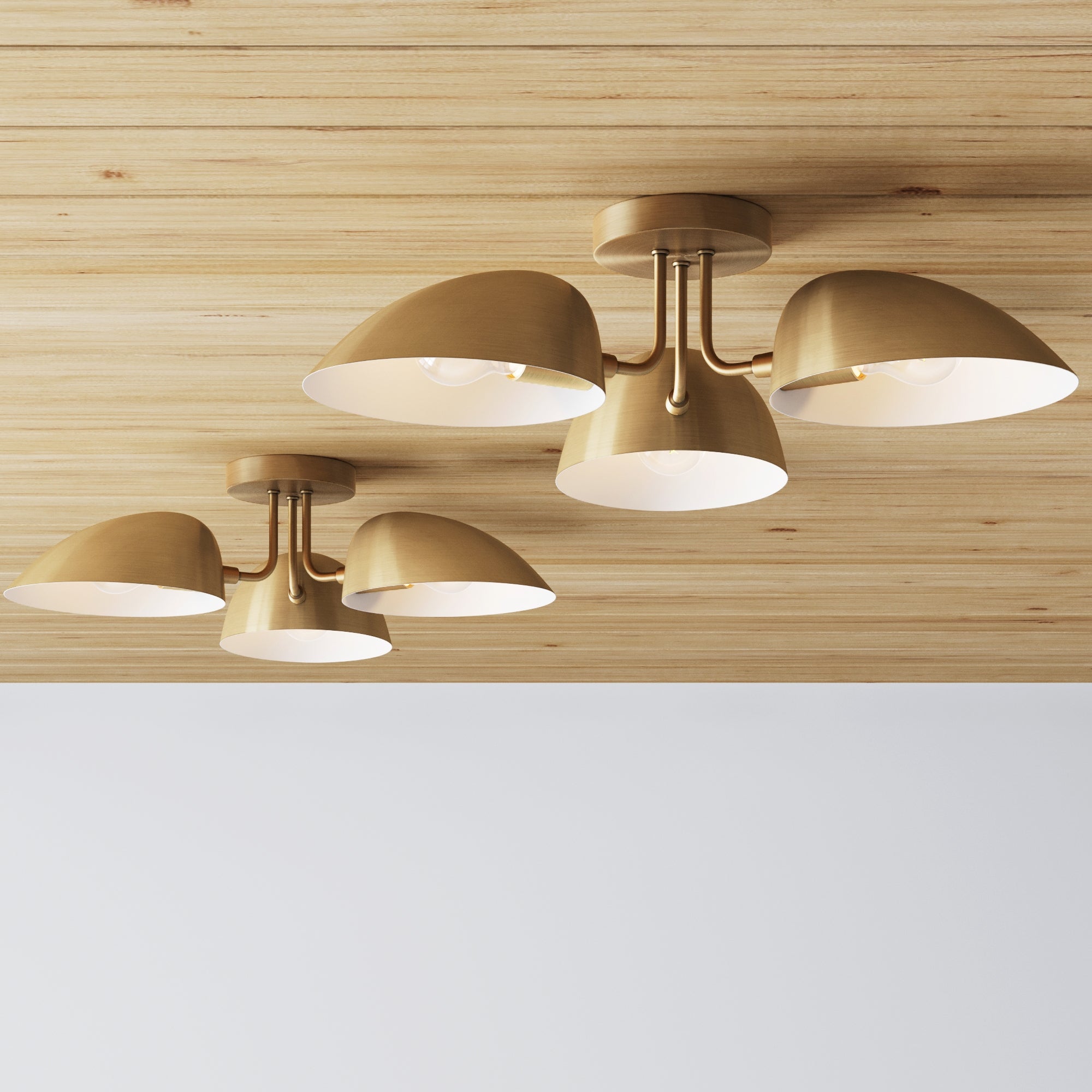 The Nathan James Metal 3-Arm Flush Mount Ceiling Light Brass (Set of 2) adds a warm, mid-century modern touch to interiors with its brass finish and trio of conical shades, enhancing any space with style above white walls.