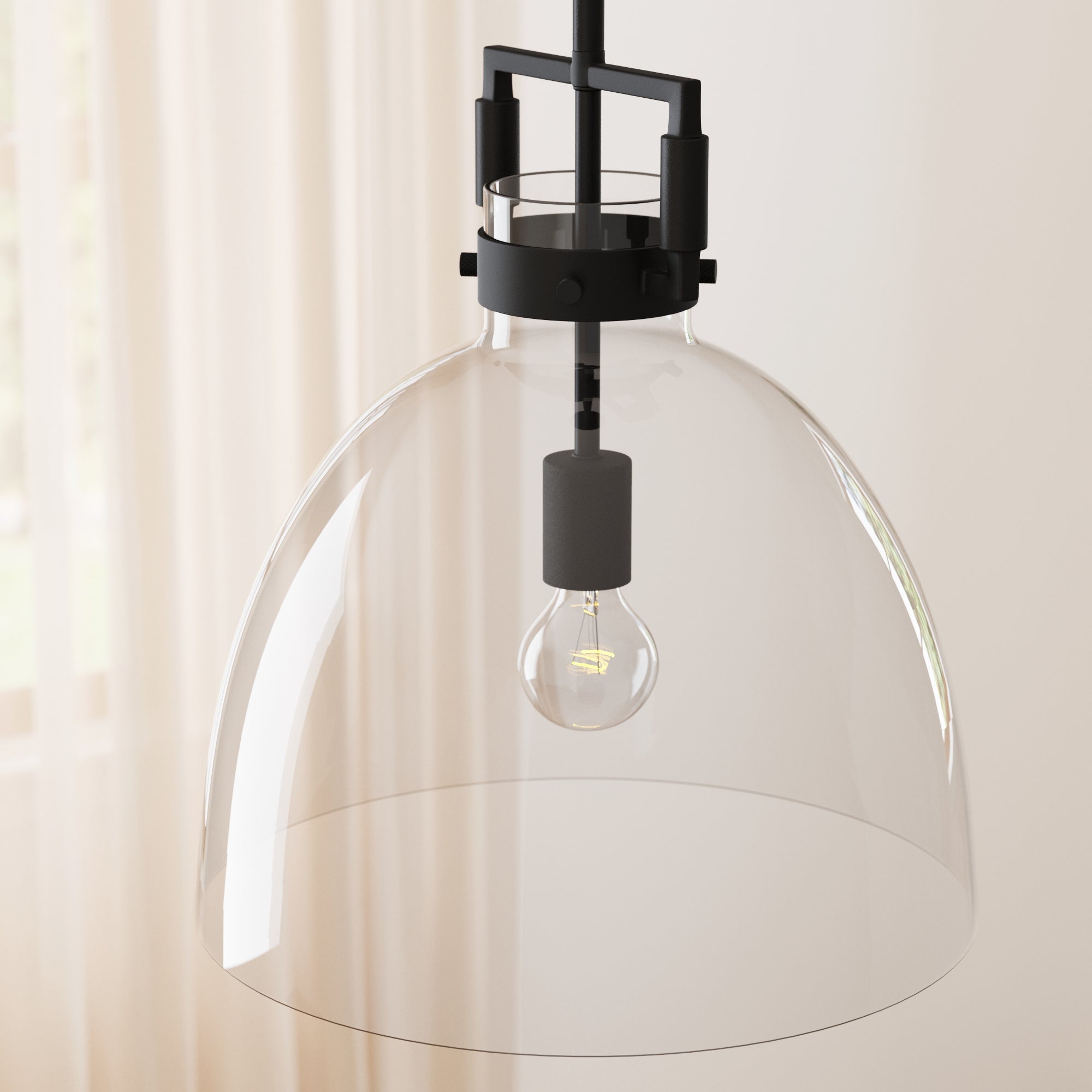 A modern pendant light with a clear glass dome shade, exposed bulb, and black metal accents, hanging in a softly lit room with sheer curtains in the background.