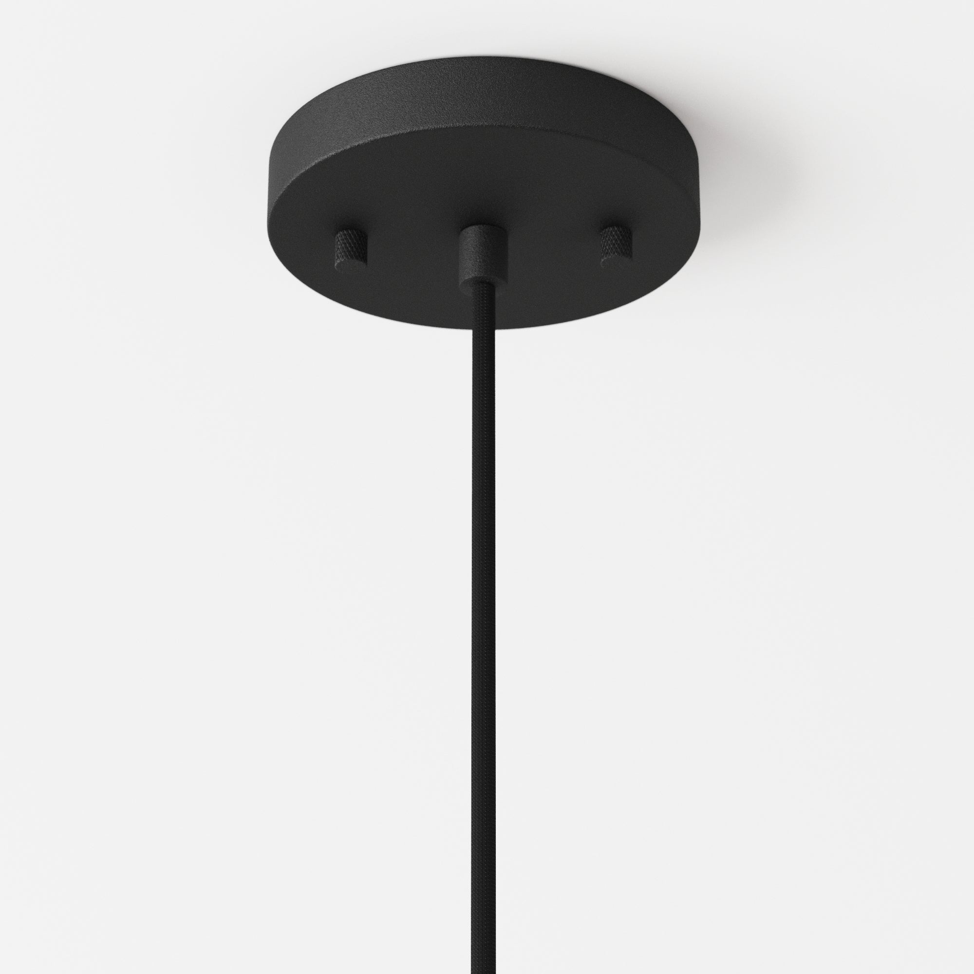 A close-up of a black ceiling-mounted light fixture canopy with a round base and a single cord hanging down against a white ceiling.