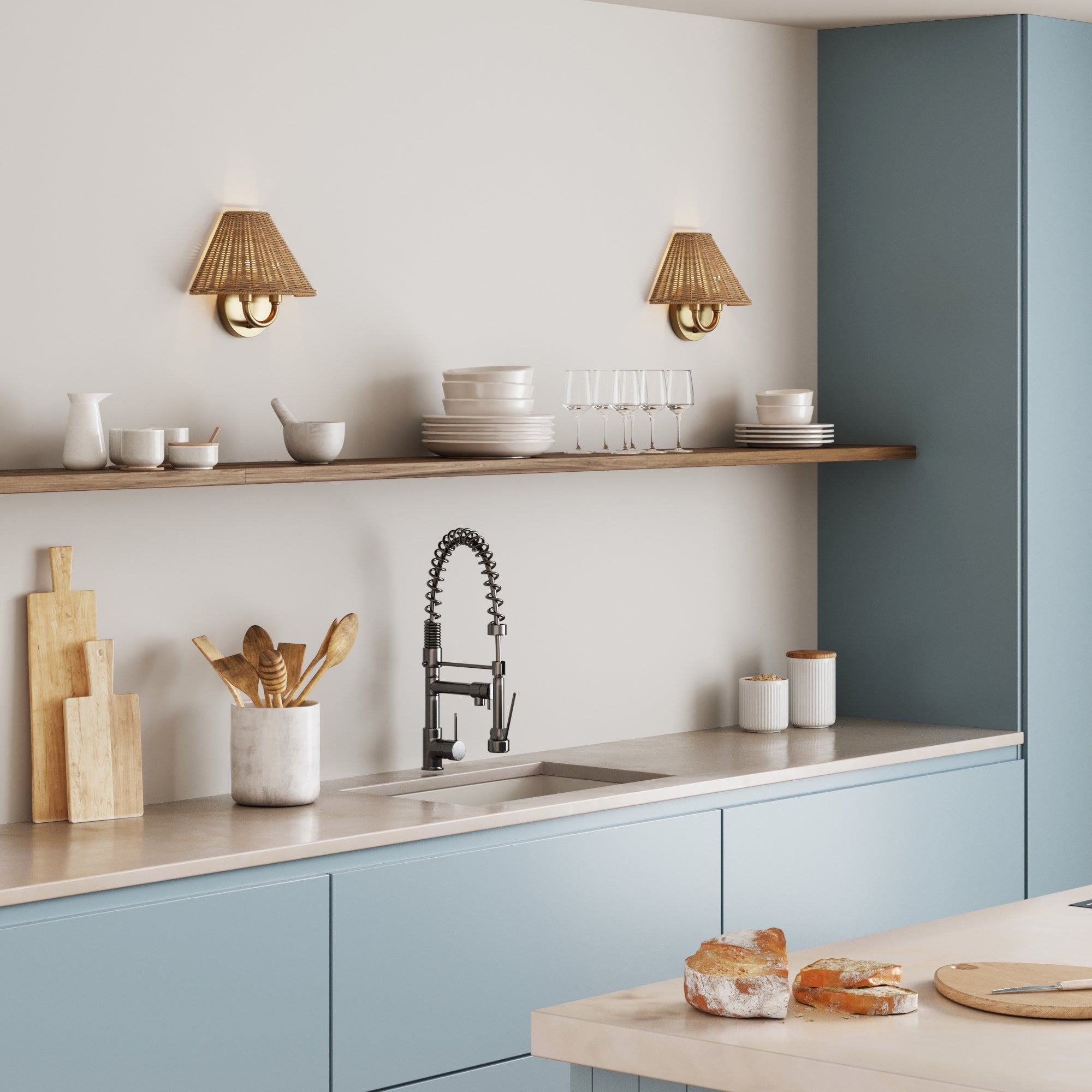 Modern kitchen with blue cabinets, stainless steel sink, black spring faucet, wooden utensils, cutting boards, open shelves with dishes and glasses, and two Nathan James Modern Farmhouse Wall Lights with Rattan Shades above.