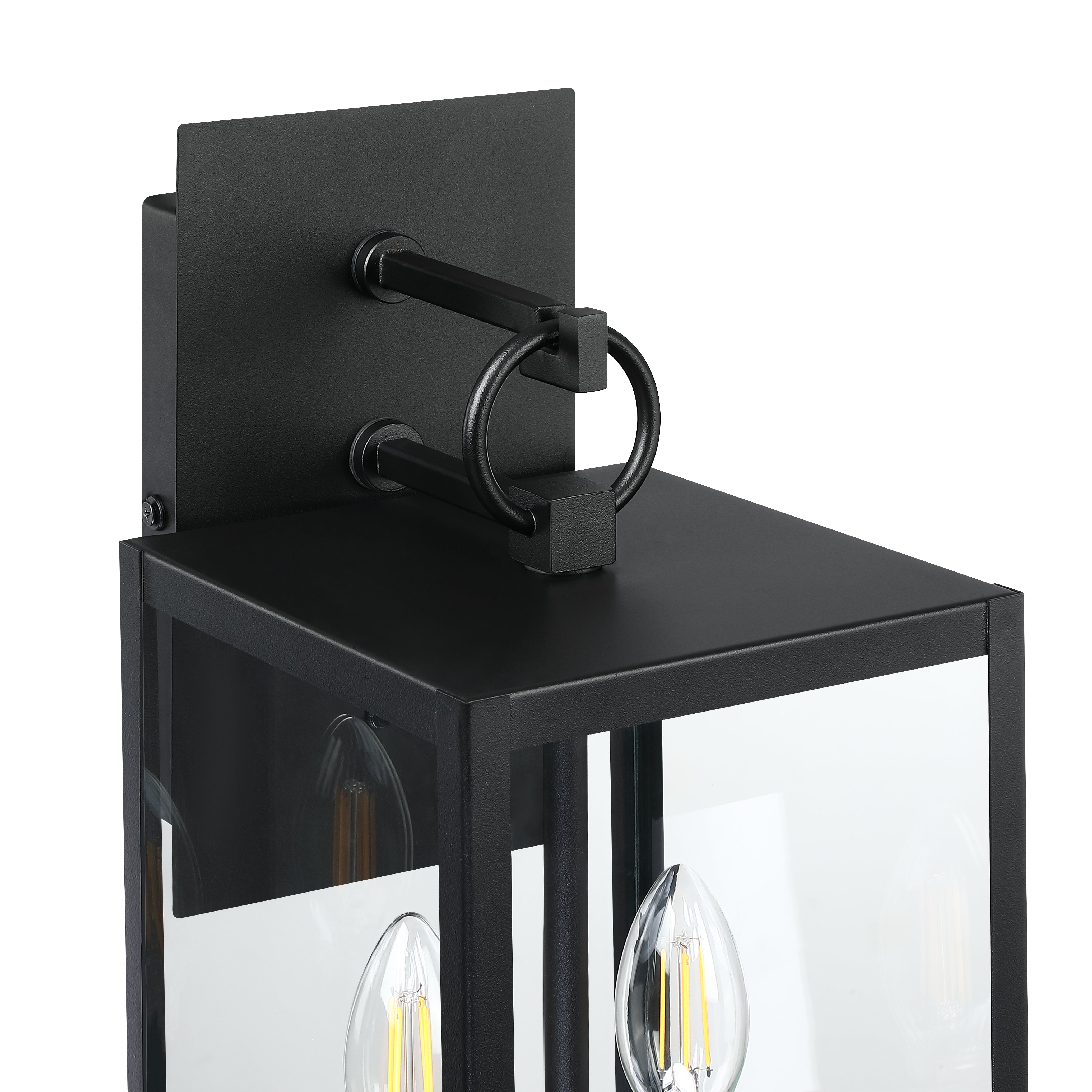 Close-up of a modern black outdoor wall lantern with a rectangular backplate, clear glass panels, and decorative ring detail at the top; candle-like LED bulbs are visible inside.