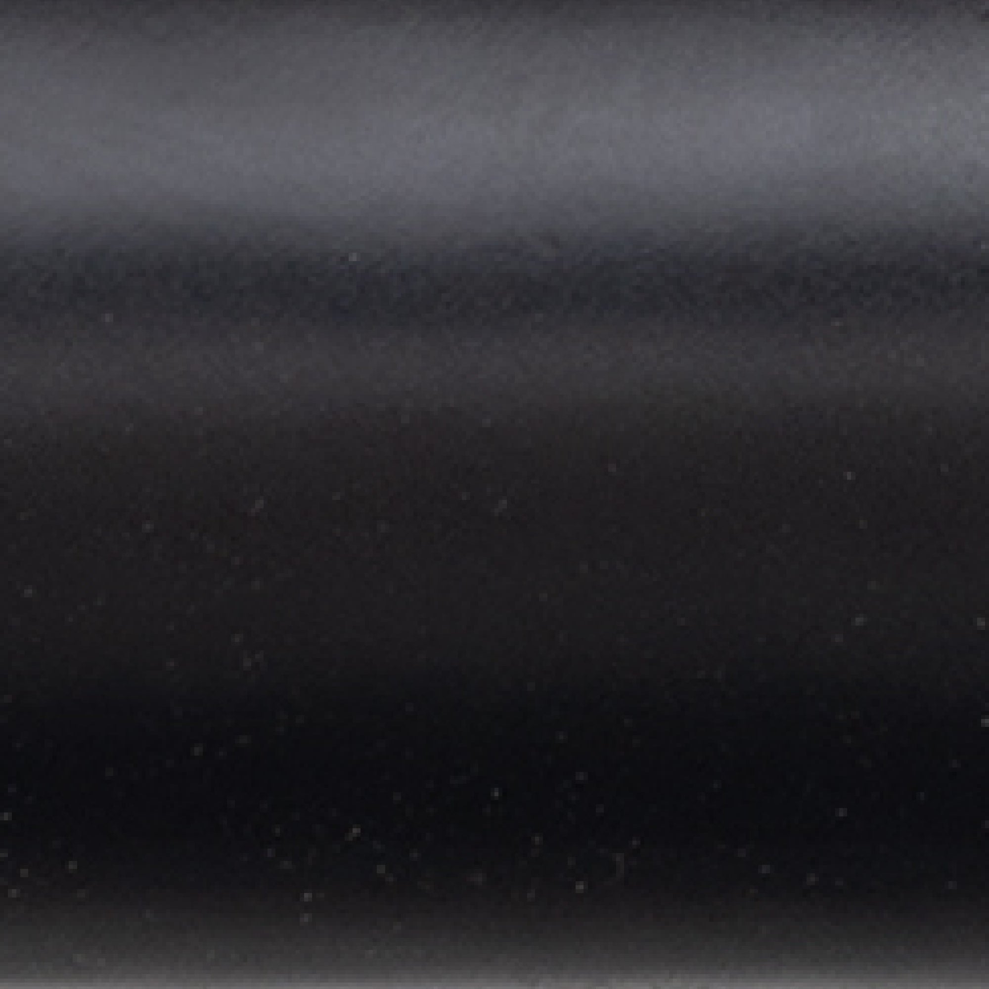 A close-up view of a smooth, dark, metallic surface with subtle reflections and small specks scattered across it.