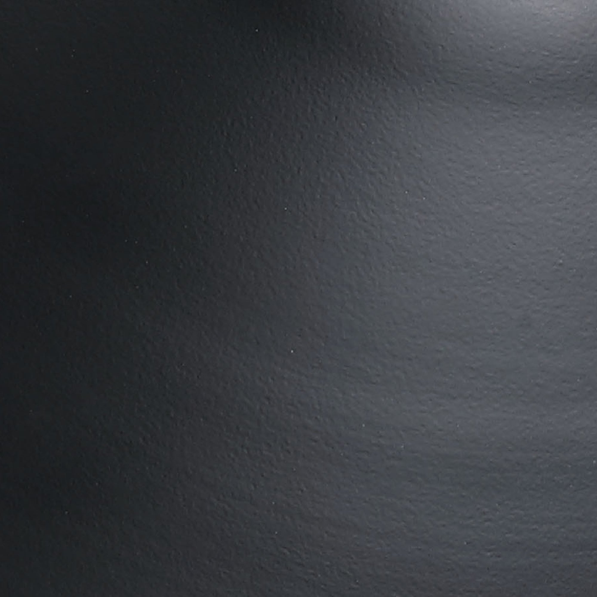 Close-up of a smooth, dark gray textured surface with a slight curve and subtle highlights, possibly metal or plastic.