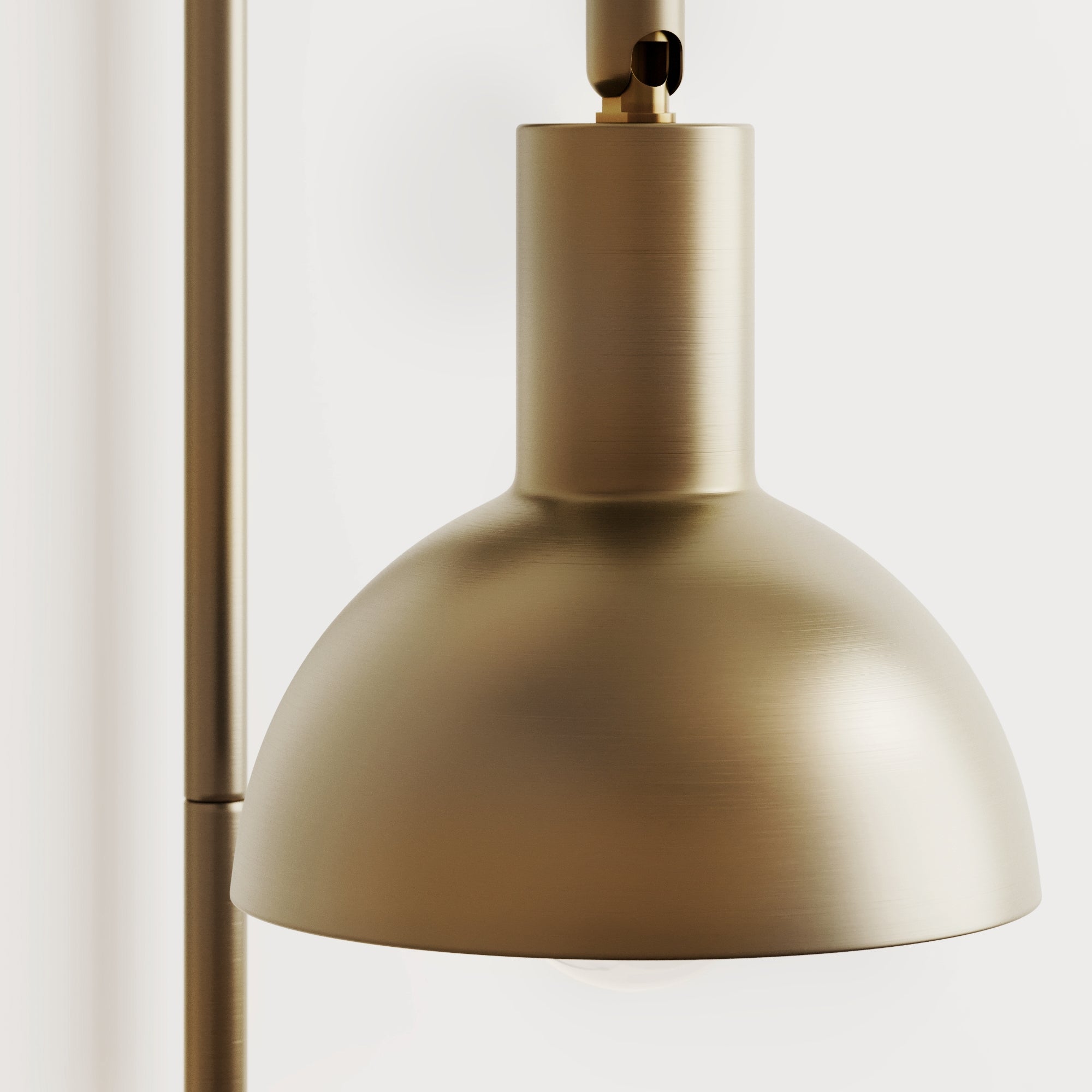 Close-up of a modern brass pendant lamp with a matte finish, featuring a dome-shaped shade and minimalist design against a plain white background.