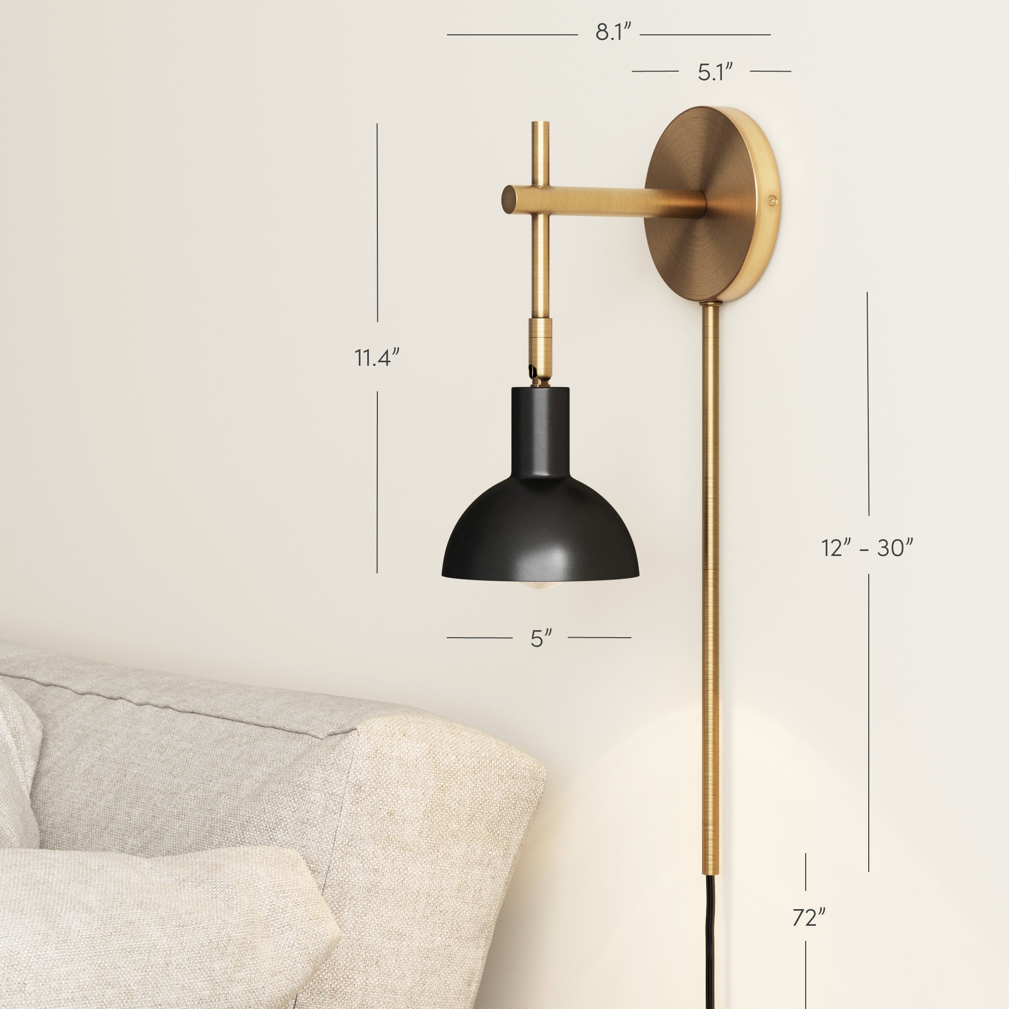 The Nathan James Plug-In Adjustable Metal Wall Light Black Brass, a modern articulating wall sconce, is installed above a beige sofa. This renter-friendly light features labeled dimensions for length, width, and height in inches.