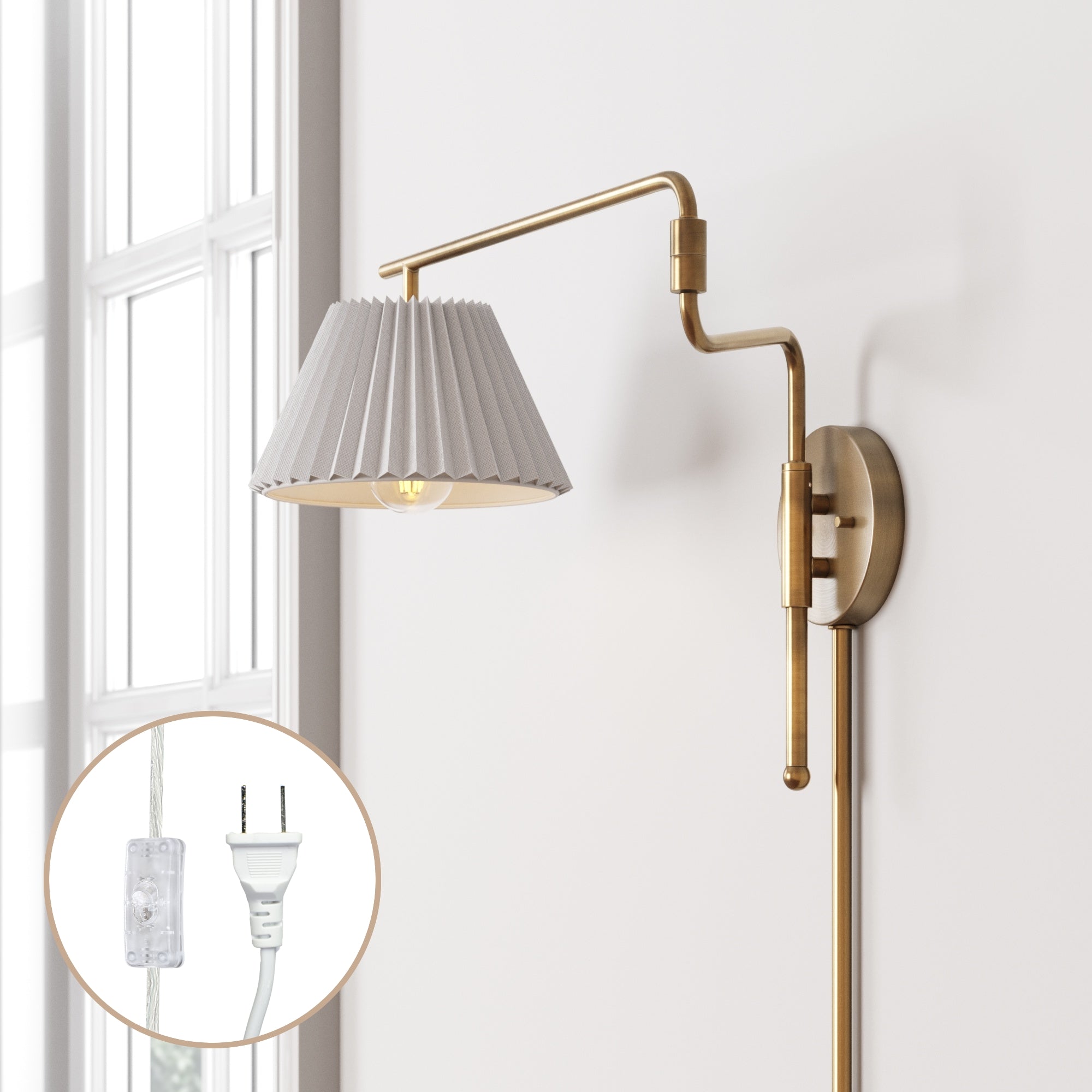 A gold wall-mounted swing arm lamp with a pleated white shade is attached to a white wall near a window. An inset shows a close-up of its clear power cord and white plug.