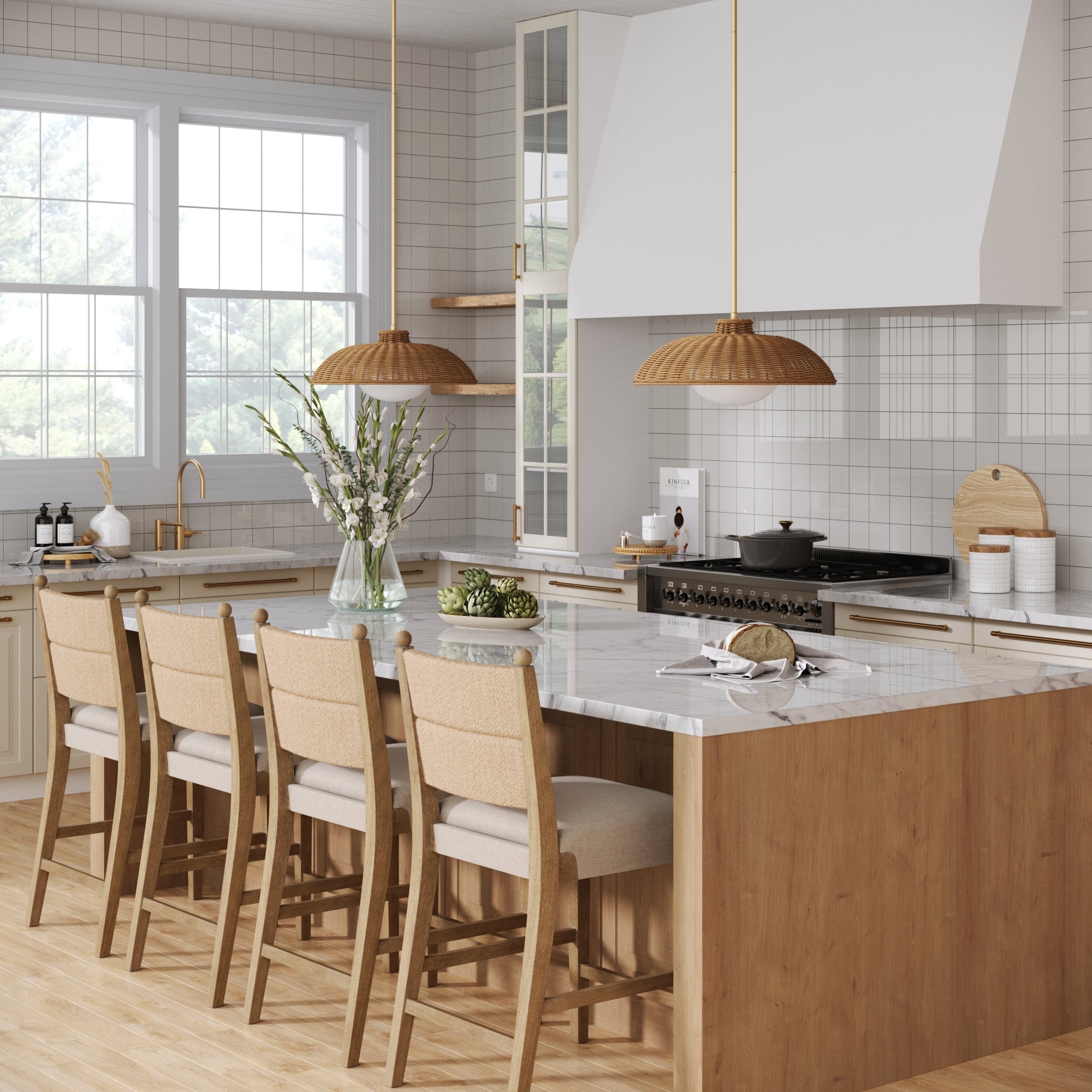 A modern kitchen with a large marble island, four Nathan James Seagrass & Wood Counter Height Bar Stools in light brown, pendant lights, light wood cabinets, a stove with white range hood, and a flower vase. Sunlight streams through a large window.