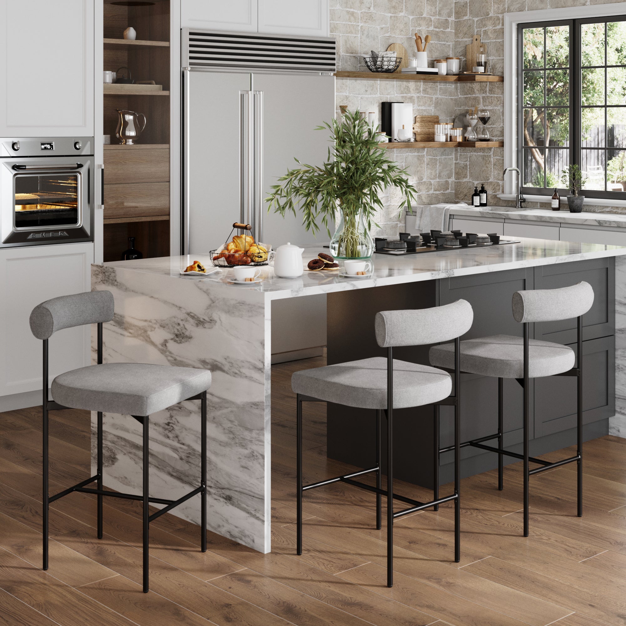 Modern kitchen with a marble island, Nathan James Metal Counter Height Bar Stools Gray (Set of 3), built-in oven, stainless steel fridge, plants, breakfast items, sunlight on wooden floors, and a stone backsplash.