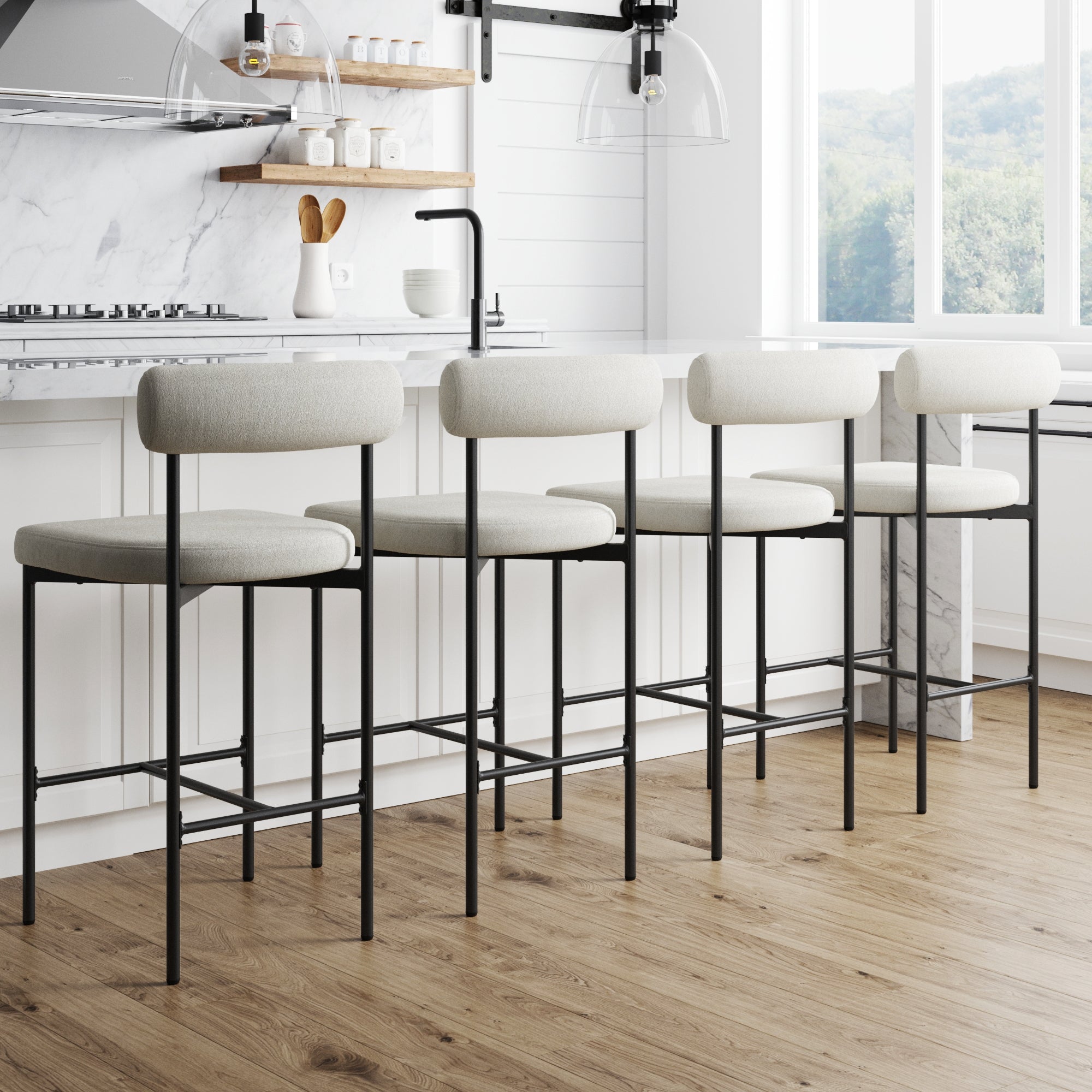 The Nathan James Boucle Counter Height Bar Stools (Set of 4) feature modern black metal frames with light cushions, perfectly lined up at a kitchen island for a sleek, minimalist look reminiscent of mid-century counter stools.