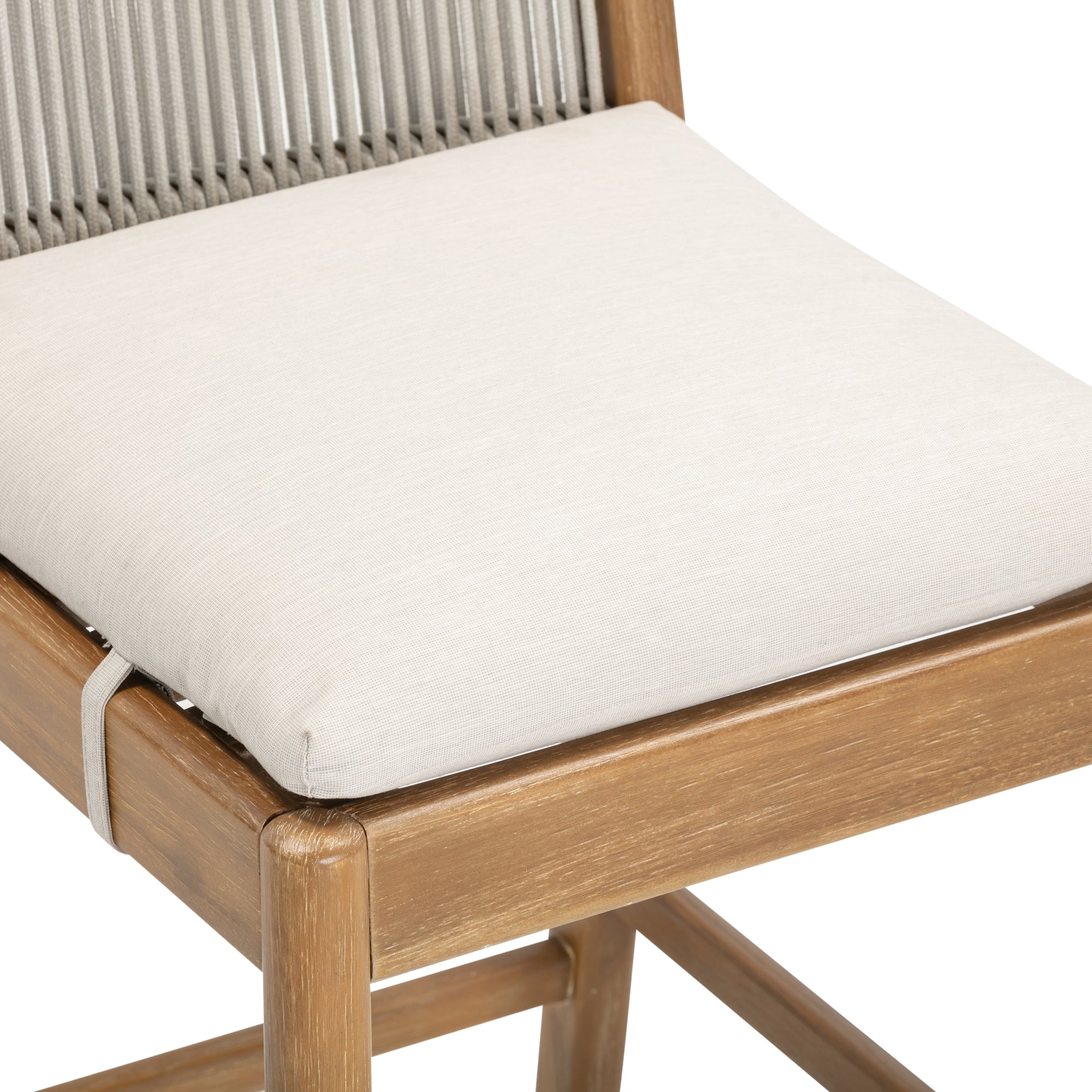 Close-up of a wooden chair with a light beige cushioned seat and woven rope backrest. The cushion is attached to the chair with a fabric strap.