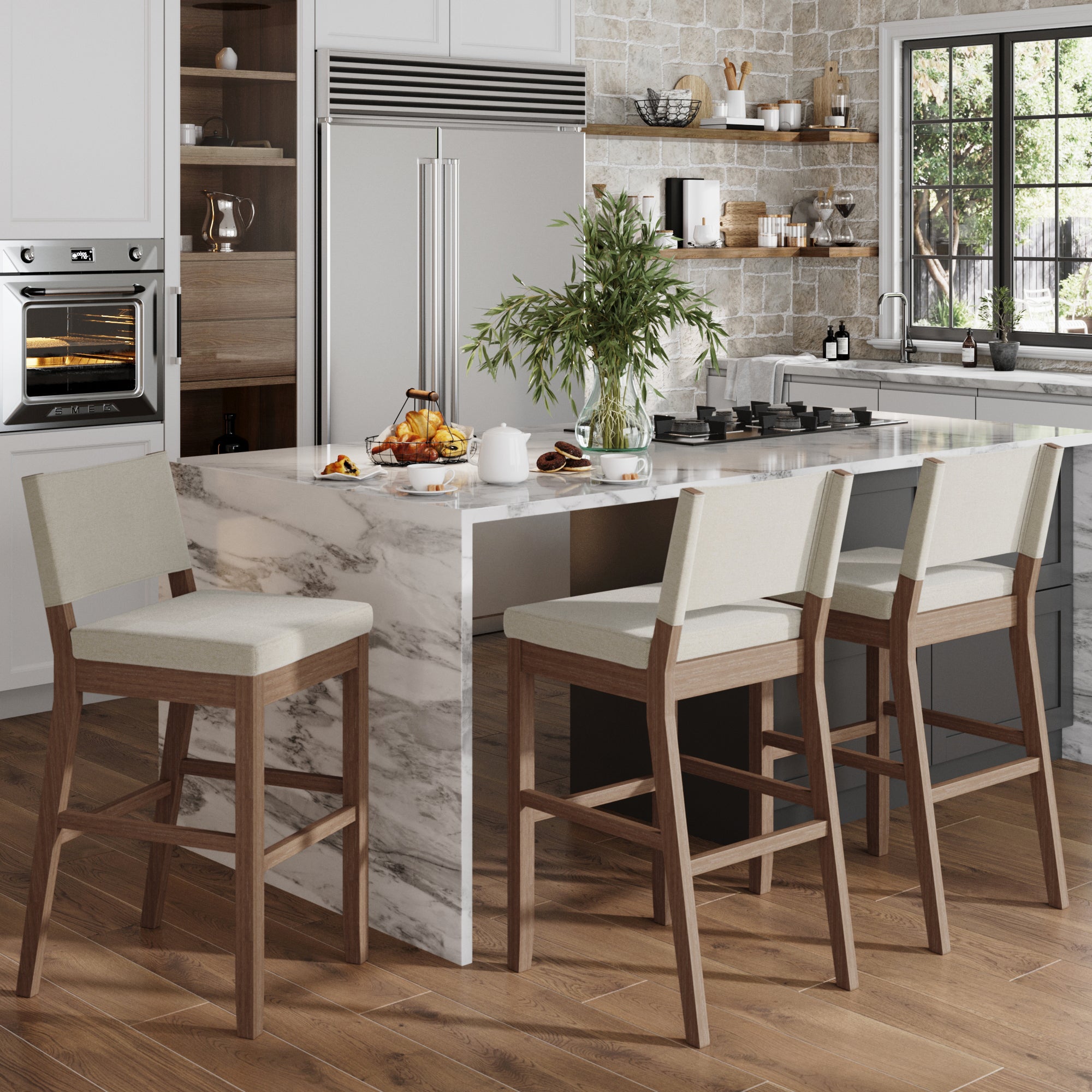 Modern kitchen with a marble island, three Nathan James Wood Upholstered Bar Stools in light brown, white cushions, built-in oven, large fridge, potted plant on the counter, and a window letting in natural light.