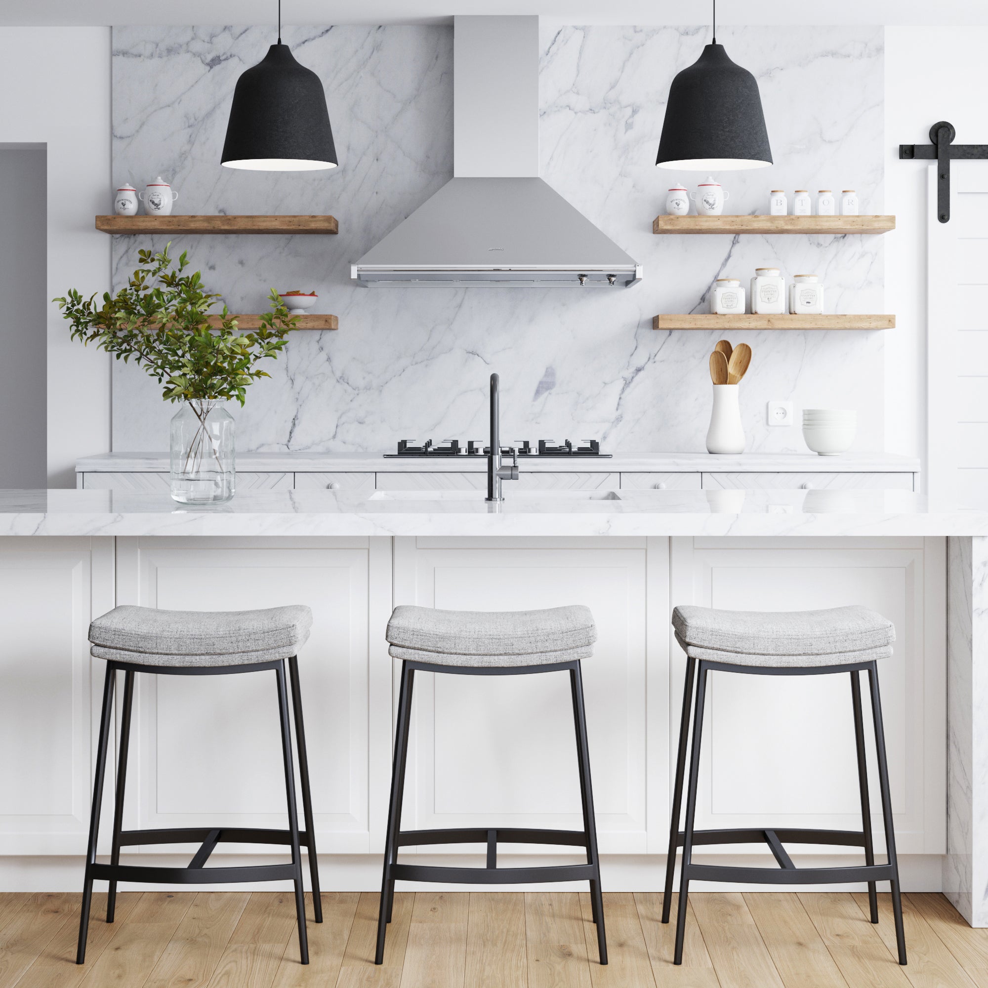 Modern farmhouse kitchen with marble backsplash and countertop, three Nathan James Upholstered Counter Height Saddle Bar Stools in Gray, a vase with greenery, open wood shelves with dishes, pendant lights, and light wood floors.