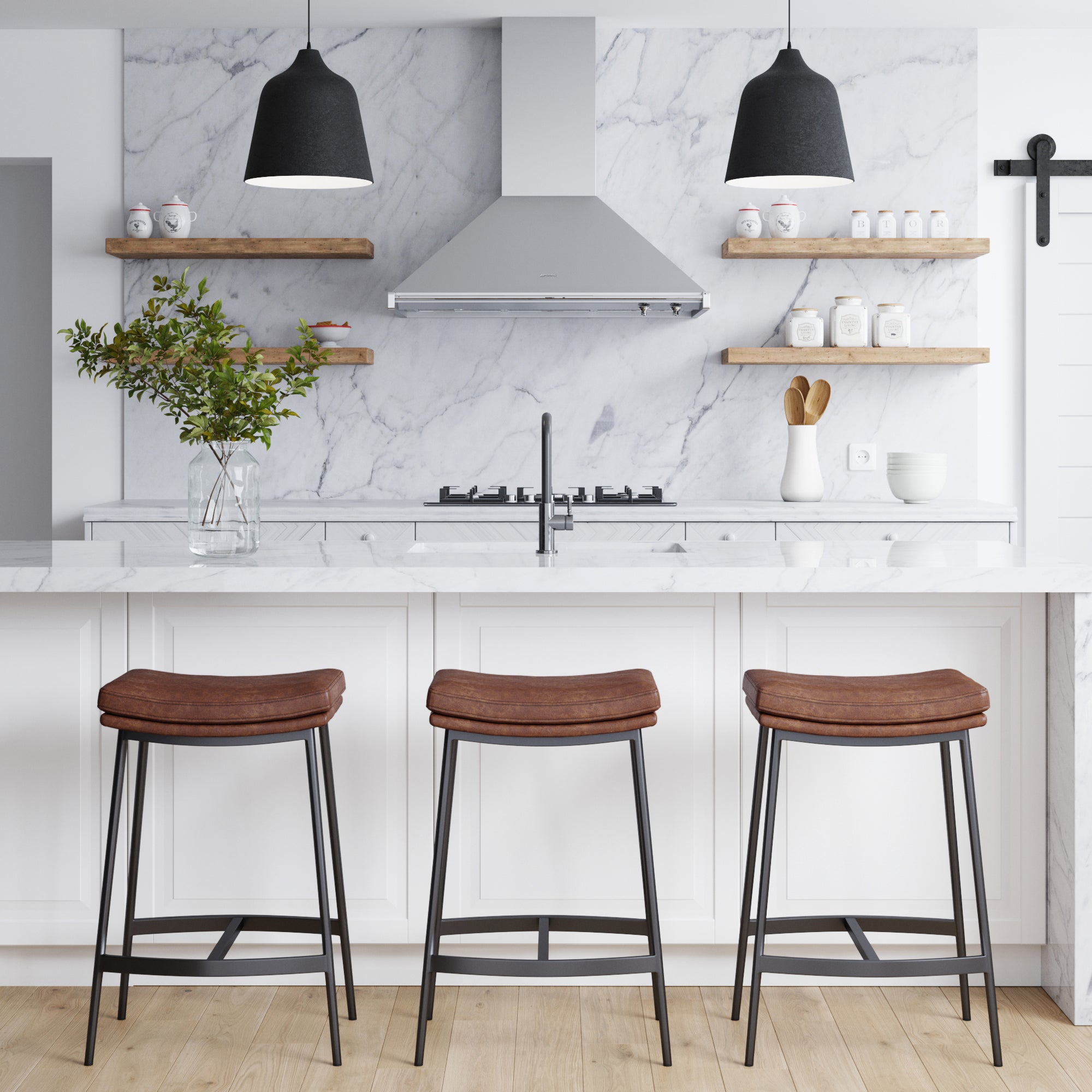 Modern farmhouse kitchen with a marble island, three Nathan James Faux Leather Counter Height Saddle Bar Stools, black pendant lights, open wooden shelves with jars and bowls, and a vase of greenery on the counter under a stainless steel range hood.