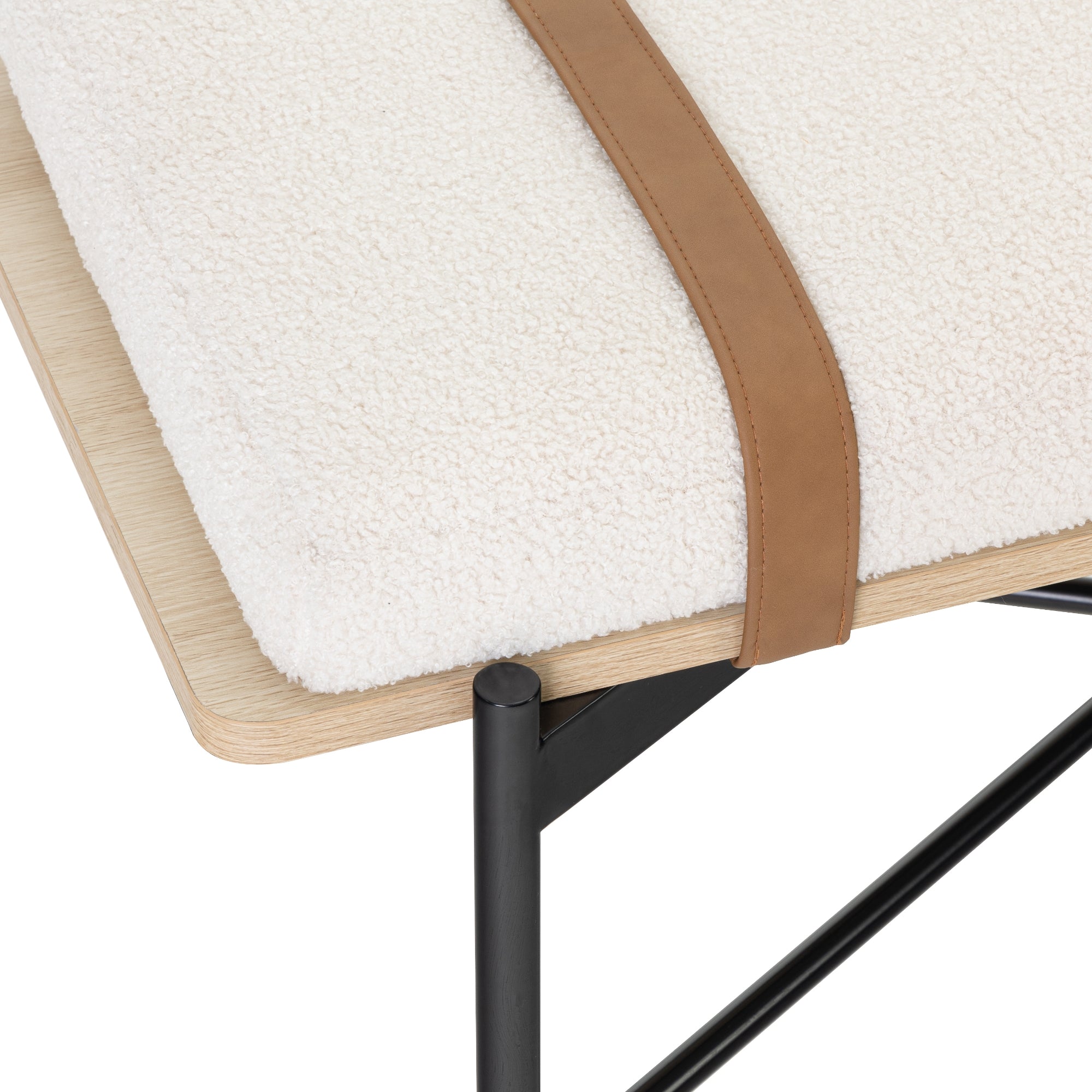 Close-up of a modern bench corner with a light wooden top, black metal legs, a textured white cushion, and a brown leather strap securing the cushion.
