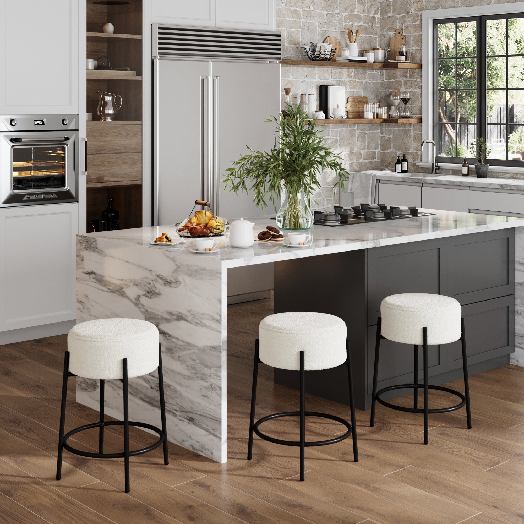Modern kitchen with a marble island, three Nathan James Round Boucle Backless Counter Height Bar Stools, built-in appliances, wood floors, shelves of dishes, and a large window. A vase with greenery sits on the island.