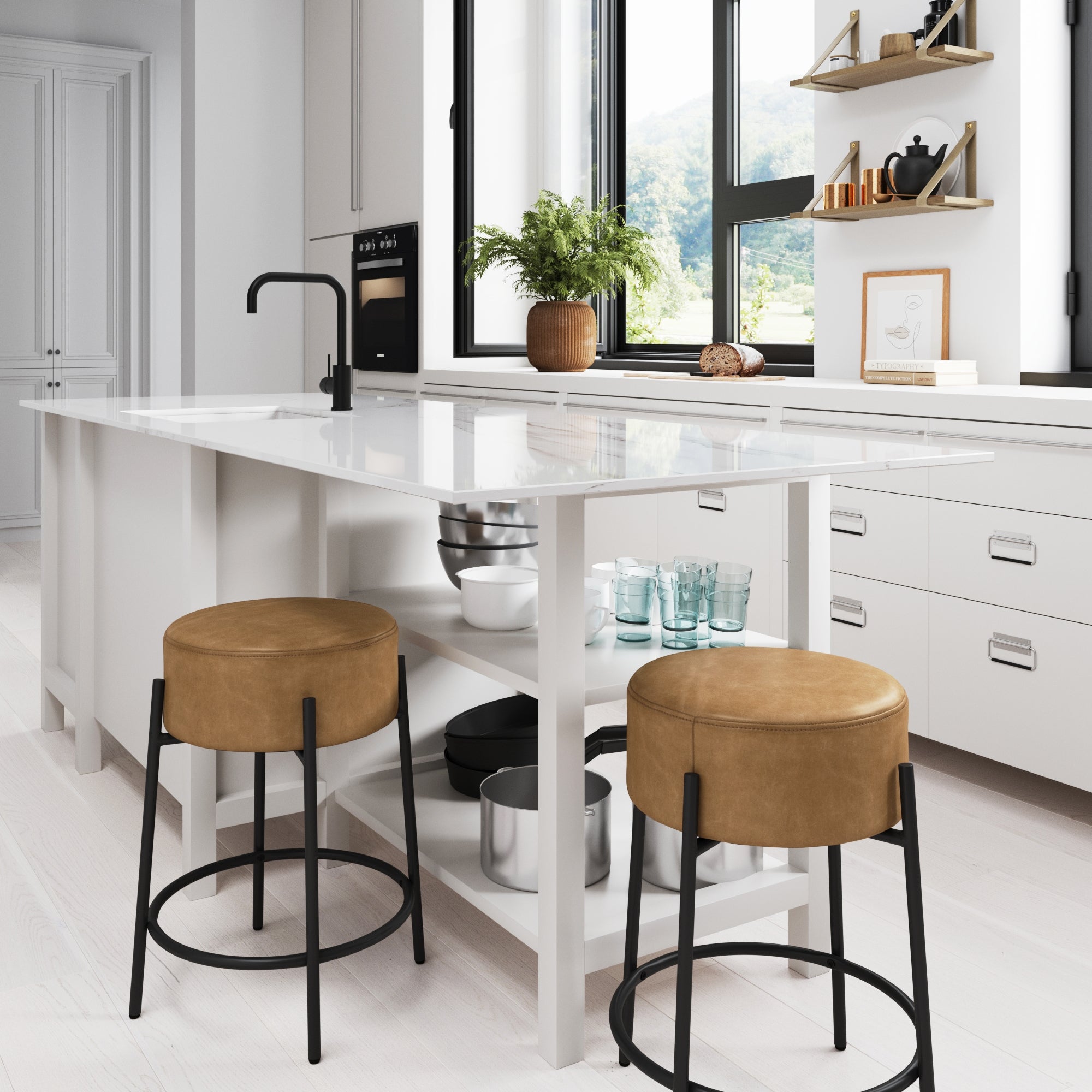 A modern white kitchen features a marble island with two Nathan James Round Faux Leather Backless Counter Height Bar Stools in brown, open shelving with decor, a potted plant, black faucet, and a large window overlooking green mountains.