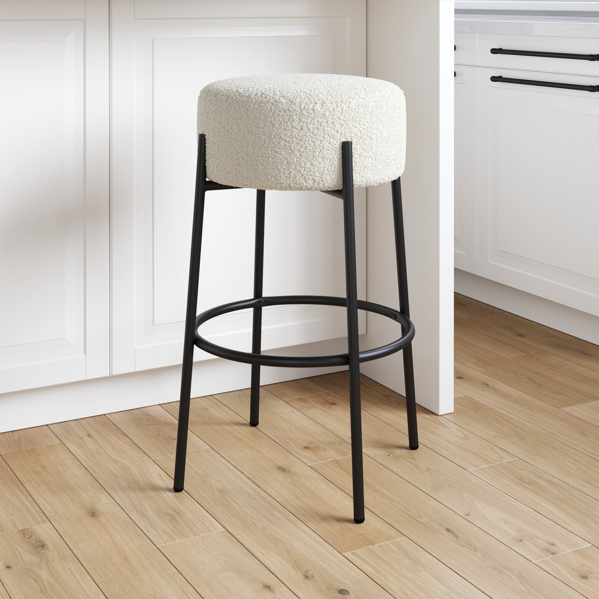 The Nathan James Round White Boucle Backless Bar Height Stool features a round, white textured cushion and black metal legs—ideal for adding sleek style to your bright kitchen island.