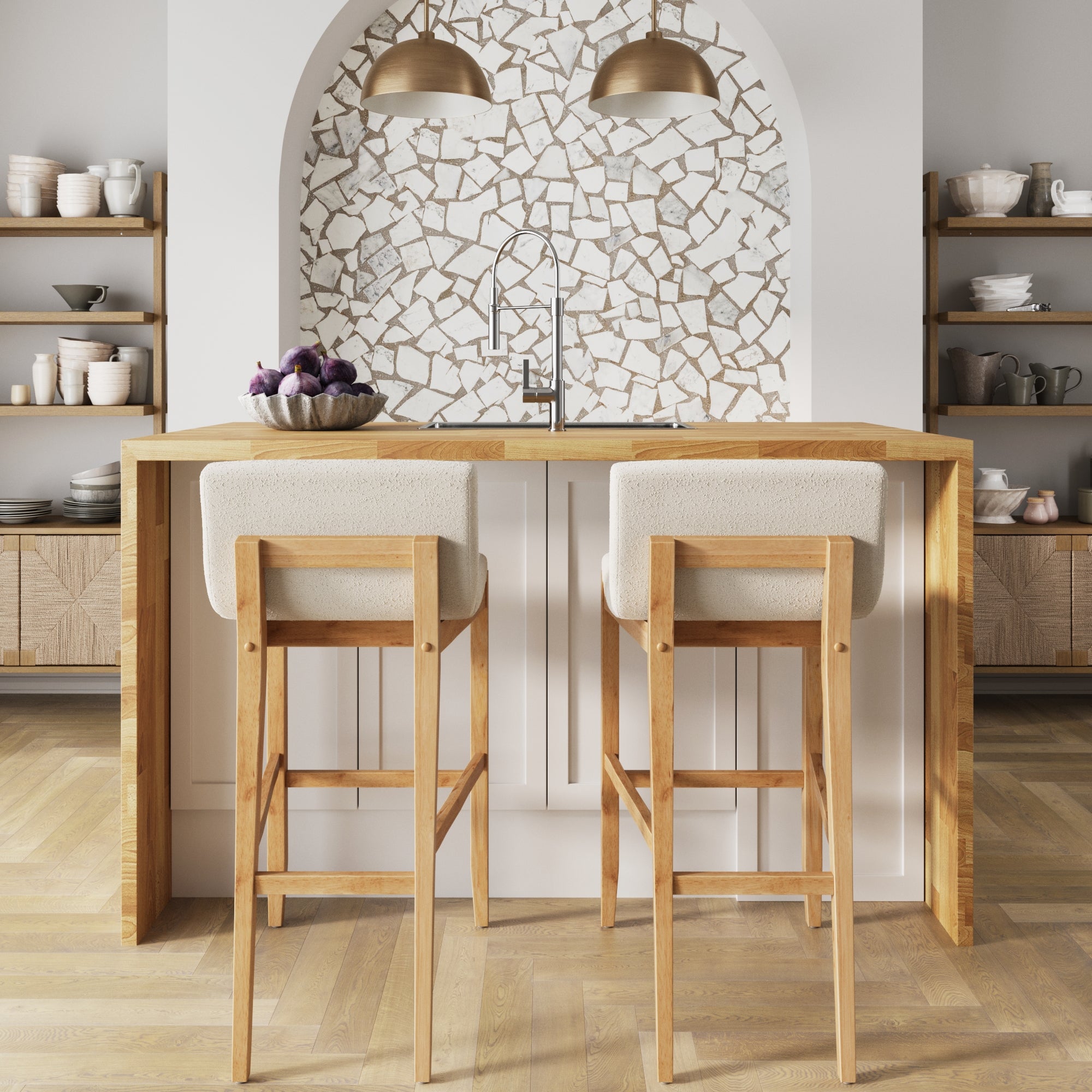 A modern kitchen features a wooden island, two Nathan James Exposed Wood Back Boucle Bar Stools in Warm Pine Boucle, a bowl of purple figs, open shelving with dishes, and a mosaic tile backsplash beneath two gold pendant lights.