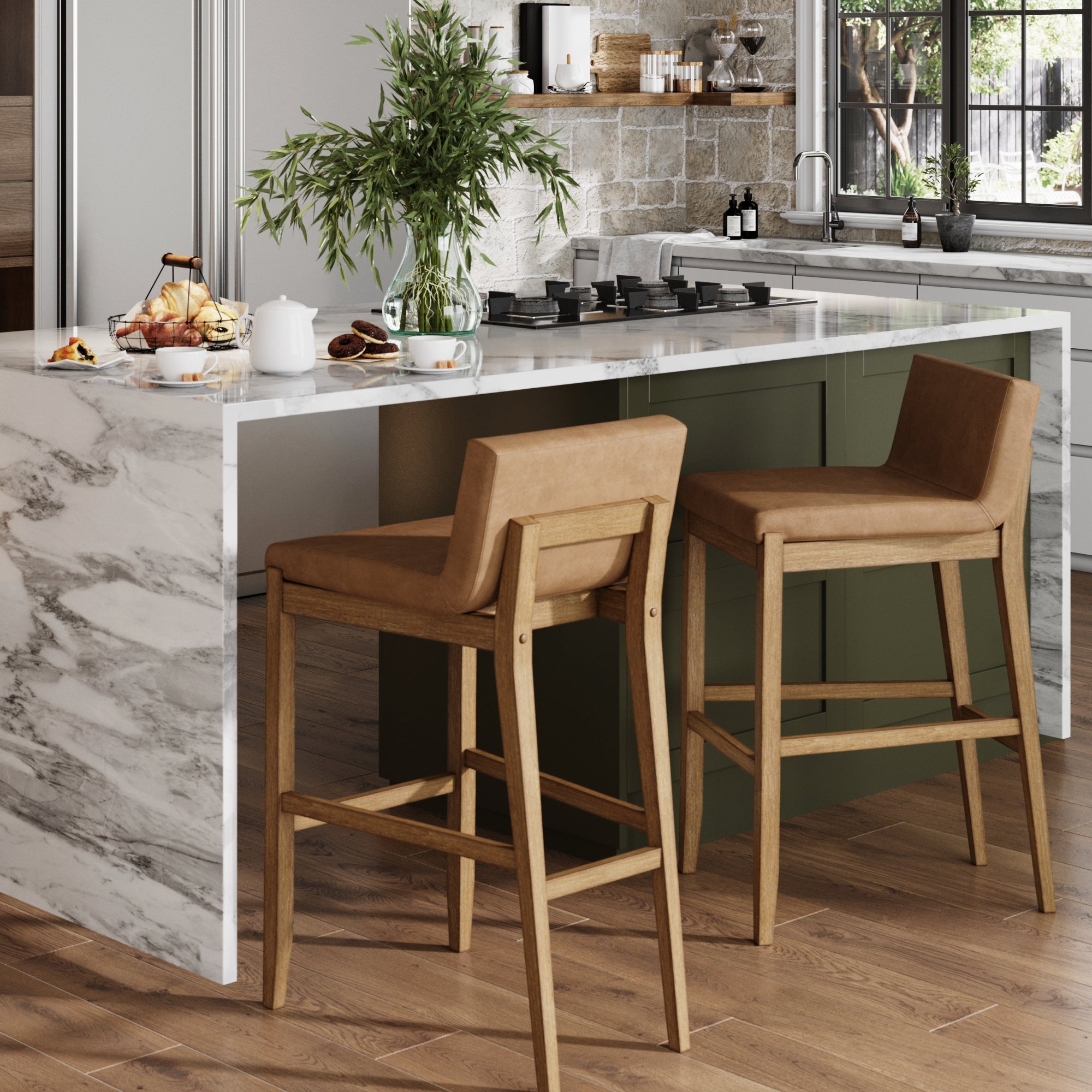 Modern kitchen with a marble island, two tan leather bar stools, wooden floors, potted greenery, breakfast items, and a window letting in natural light.