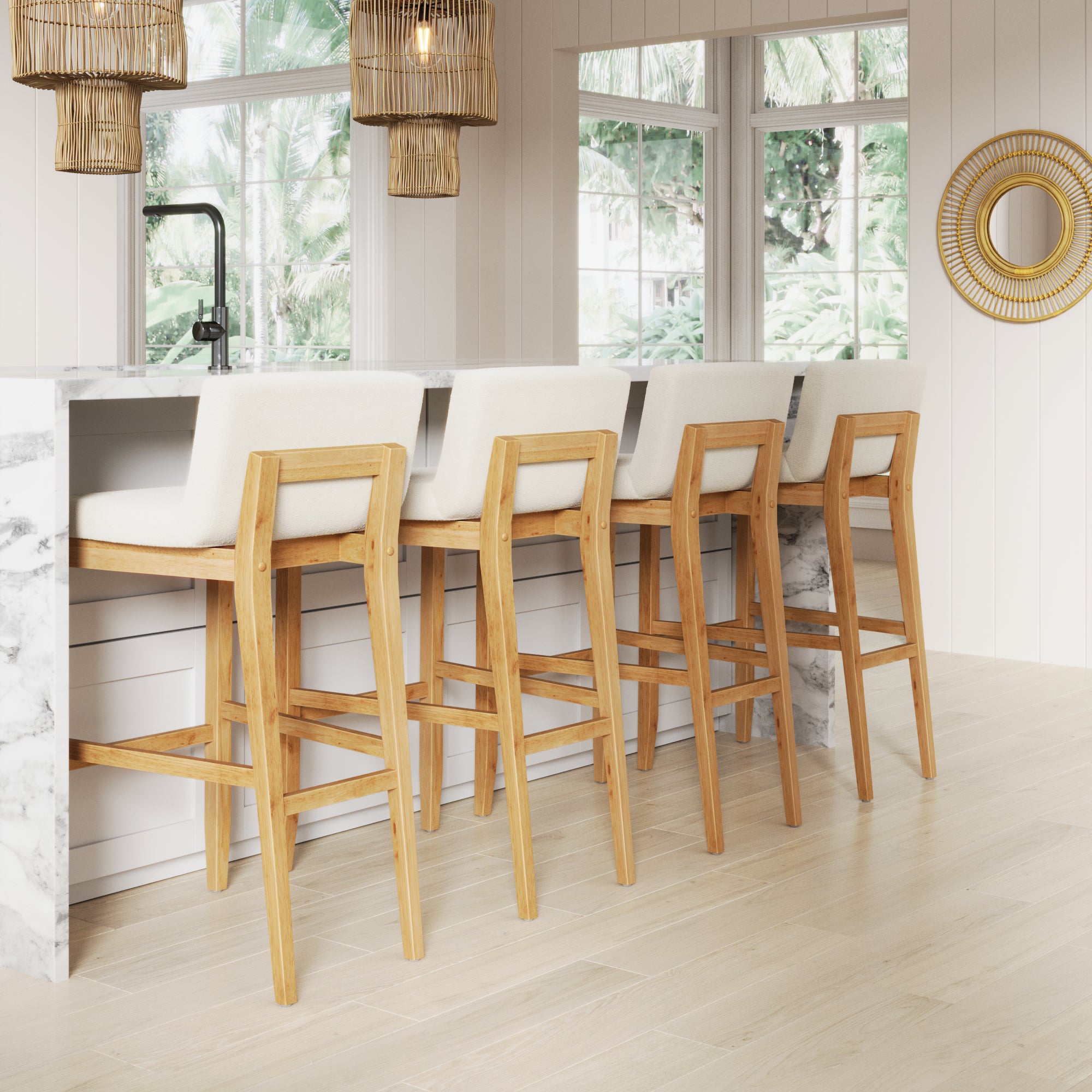 Four Nathan James Exposed Wood Back Boucle Bar Stools in warm pine with white boucle seats (set of 4) are arranged along a marble kitchen island in a bright, airy space with large windows, pendant lights, and a round mirror on a paneled wall.