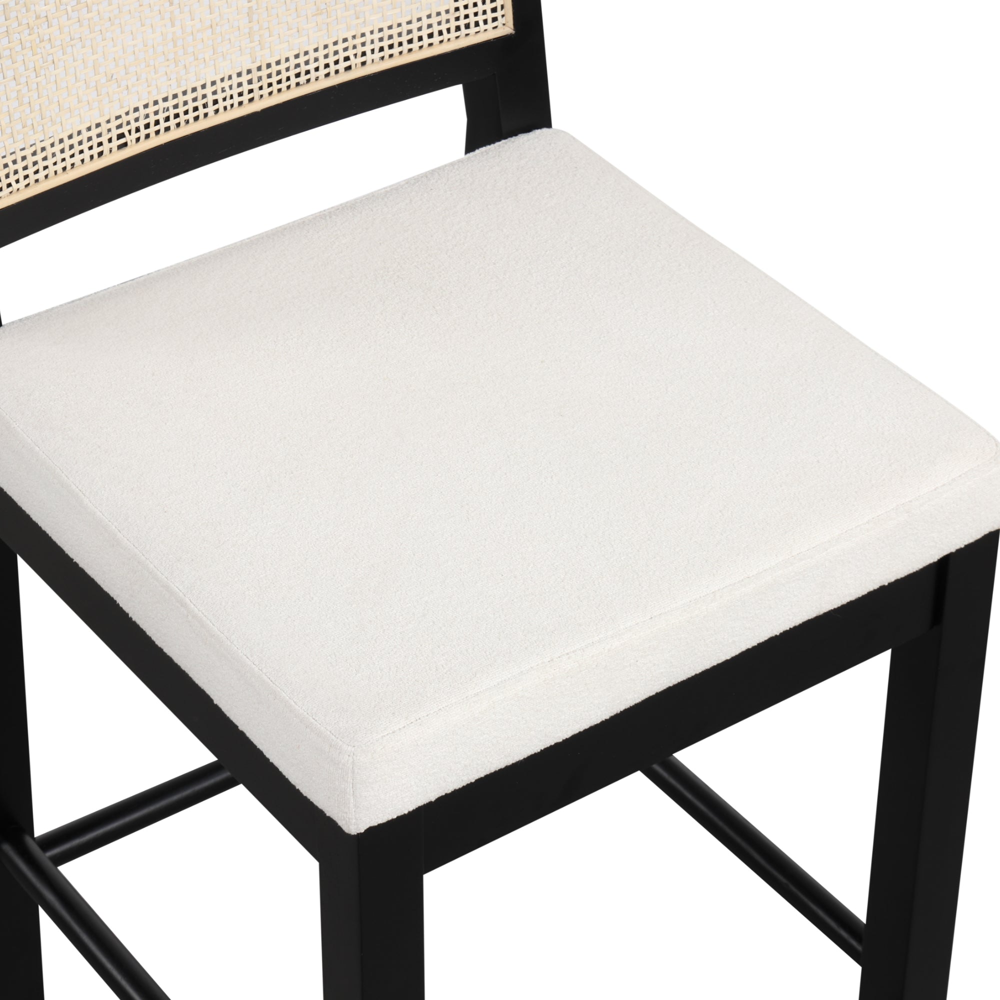 A close-up of a chair with a white cushioned seat, black wooden frame, and a backrest featuring a woven rattan design.