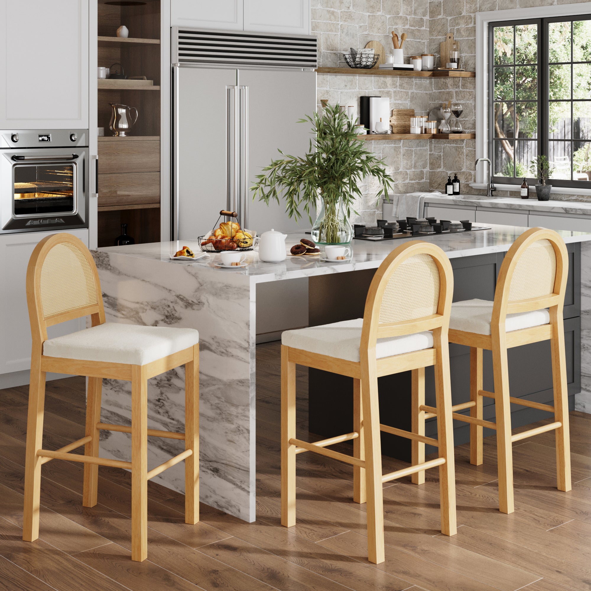 Modern kitchen with a marble island, three Nathan James Boucle & Rattan Bar Stools in Warm Pine, built-in appliances, potted plants, and large windows bringing in natural light.