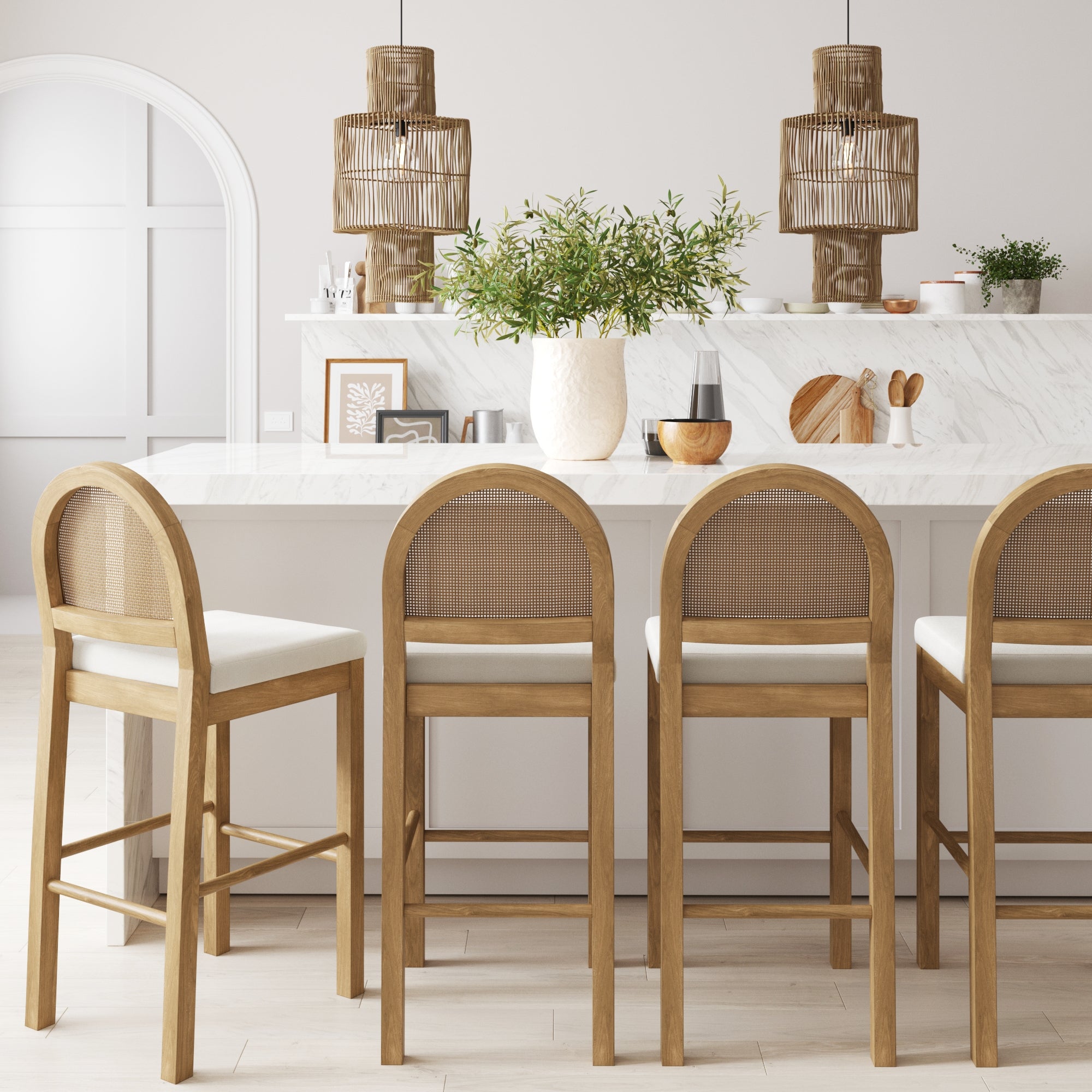A bright, minimalist kitchen features a white marble island, four Nathan James Boucle Bar Stools in light brown, two pendant lights, a vase with greenery, and decorative items on the counter.