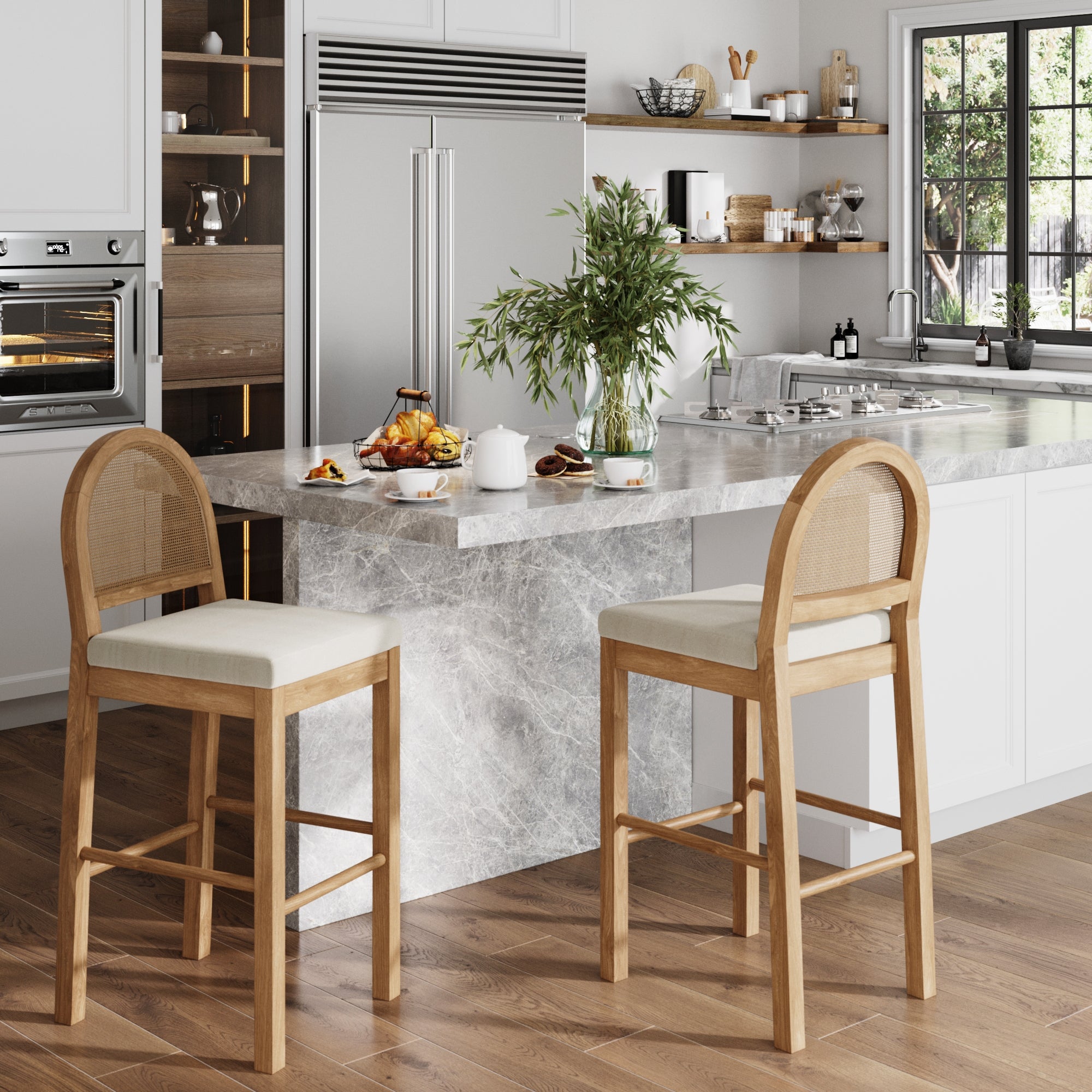 Modern kitchen with a marble island, two Nathan James Boucle & Rattan Bar Stools in light brown, cushion seats, teapot, cups, pastries, and a vase with greenery on the counter. Stainless steel fridge and open shelves complete the boho look.
