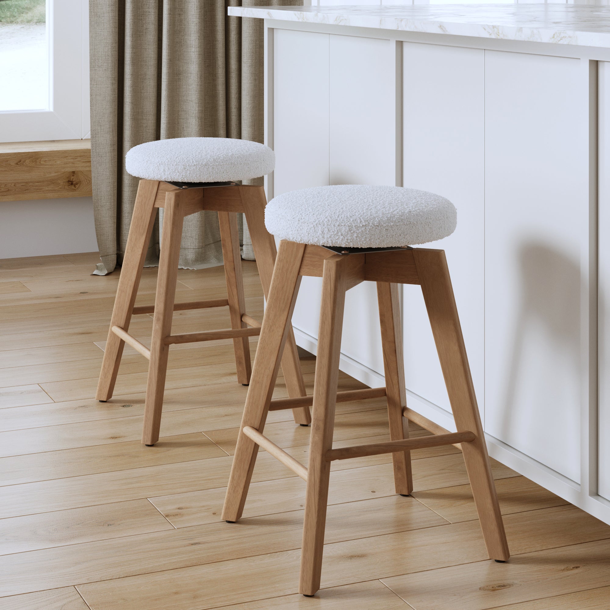 The Nathan James Wood Boucle Counter Height Swivel Stools (Set of 2) in White Oak feature round white cushioned seats and are placed by a white kitchen island on a light wood floor with natural light streaming in.