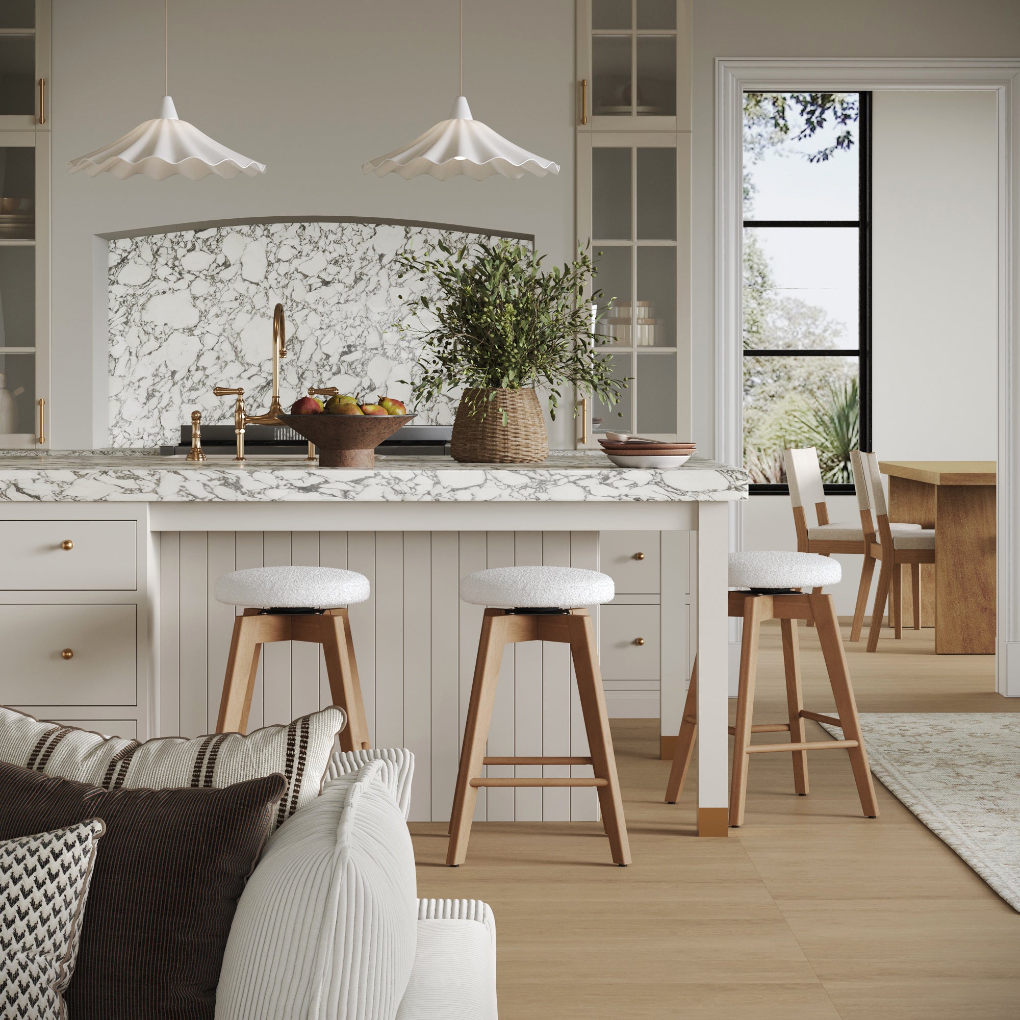 A modern kitchen with a marble island, Nathan James Wood Boucle Counter Height Swivel Counter Stools in White Oak (Set of 3), pendant lights, a fruit bowl, and plants. The dining area is visible through an open doorway.