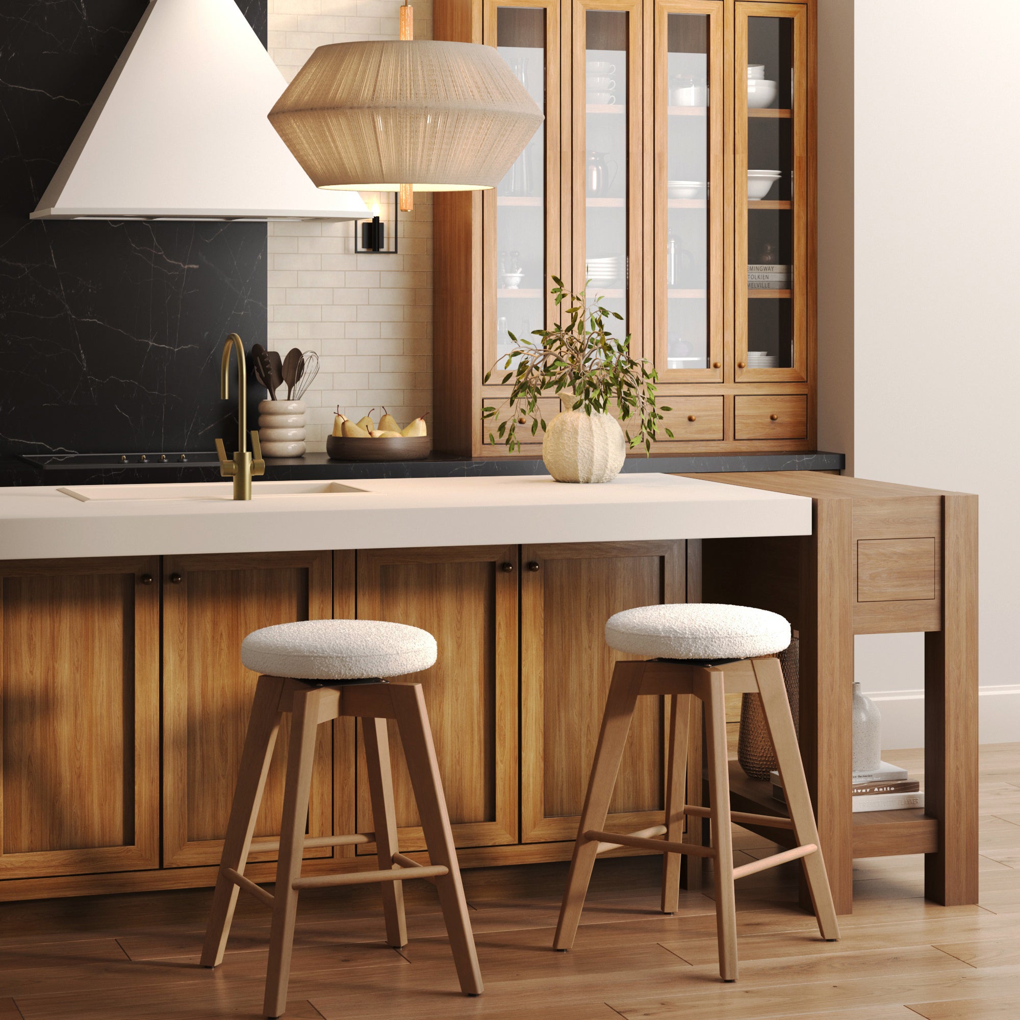 A modern kitchen features wooden cabinets, a white island, and two Nathan James Wood Boucle Counter Height Swivel Counter Stools in White Oak. A pendant light hangs above, and a vase with greenery decorates the countertop.