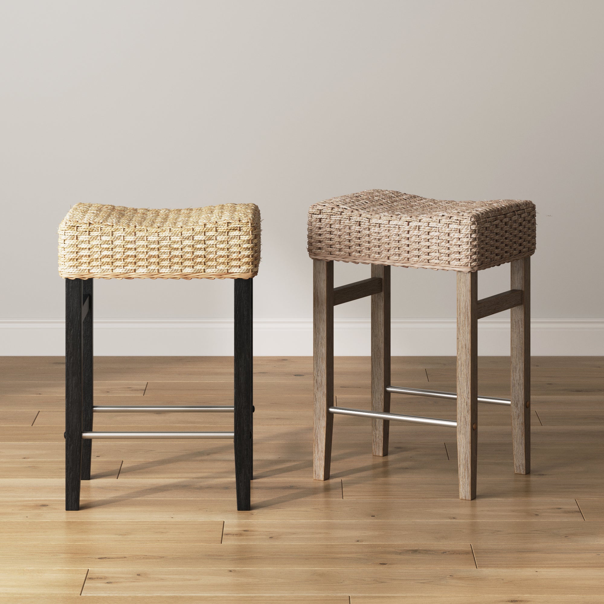 Two woven bar stools with rectangular seats and four legs, positioned side by side on a wooden floor against a plain, light-colored wall. One stool has darker legs and a lighter seat; the other has lighter legs and a slightly darker seat.