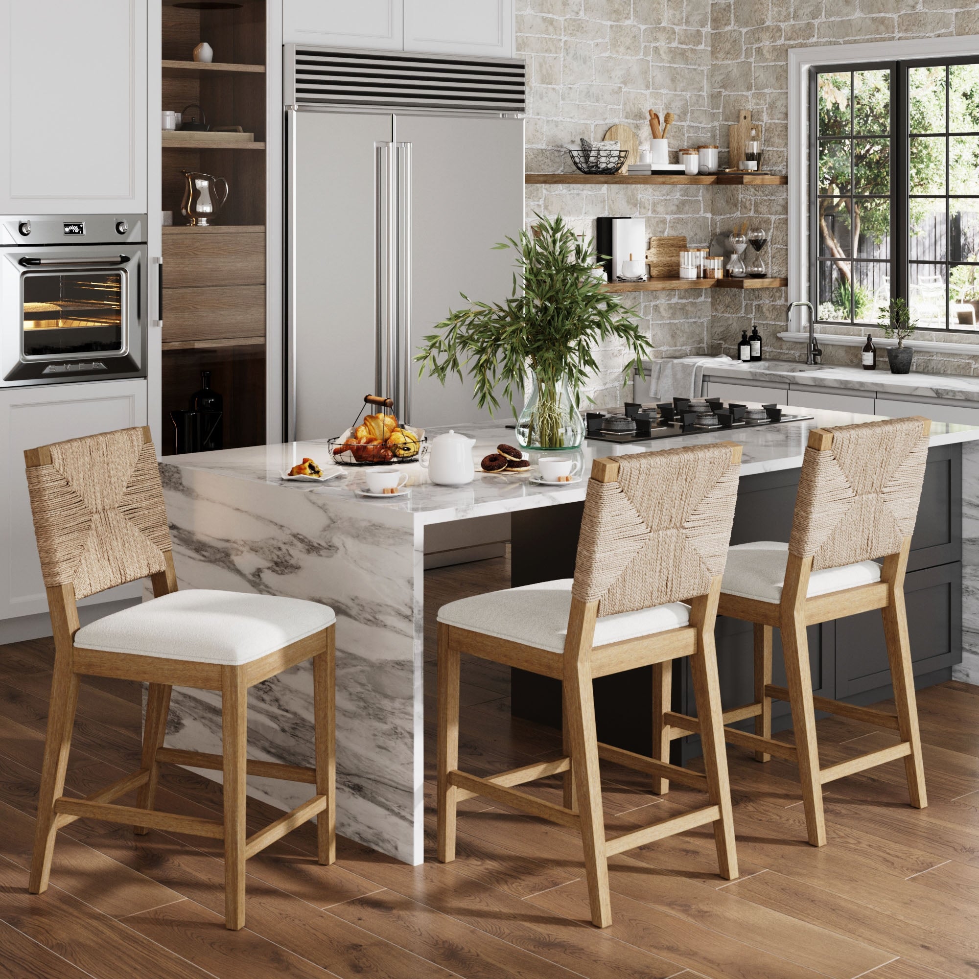 A modern kitchen with a marble island, three Nathan James Seagrass Counter Height Bar Stools in light brown, stainless steel appliances, a potted plant, and a large window. Light wood floors and stone backsplash complete the look.