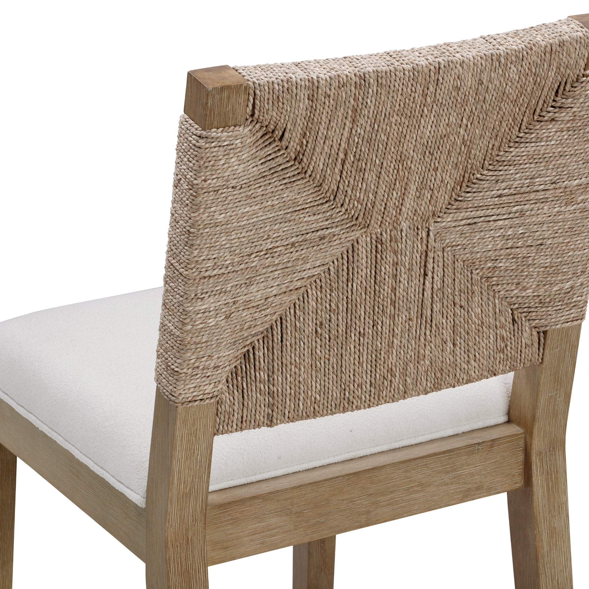 A close-up of a wooden chair with a woven backrest made of natural fiber and a cushioned white seat. The woven pattern creates a geometric design on the back of the chair.