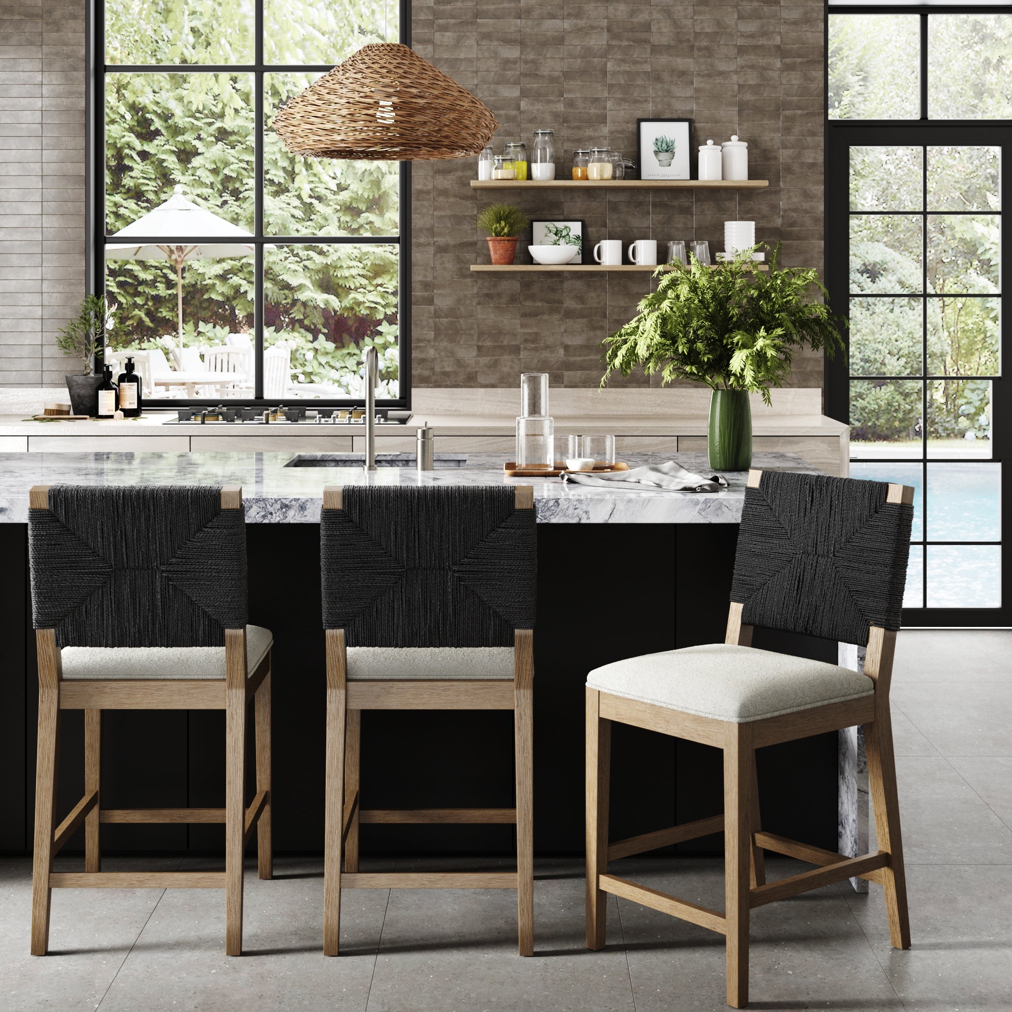 Modern kitchen with Nathan James Boucle & Seagrass Black Counter Height Bar Stools (Set of 2) at a marble island, potted plants, shelves of dishes, pendant lighting, and large windows overlooking a patio with greenery and pool.