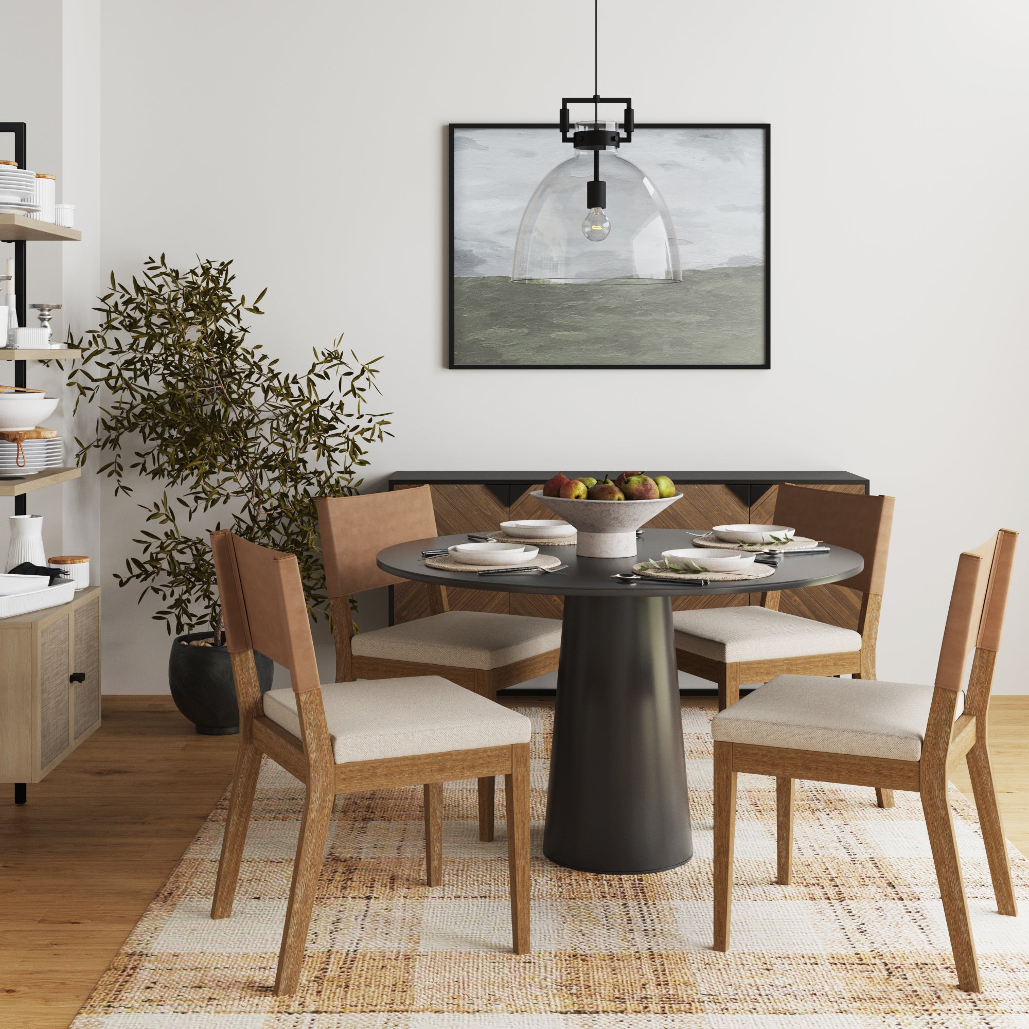 A modern dining room with a round black table, four wooden chairs with beige cushions, a bowl of fruit in the center, a potted plant, wall art, shelves with dishes, and a hanging pendant light.