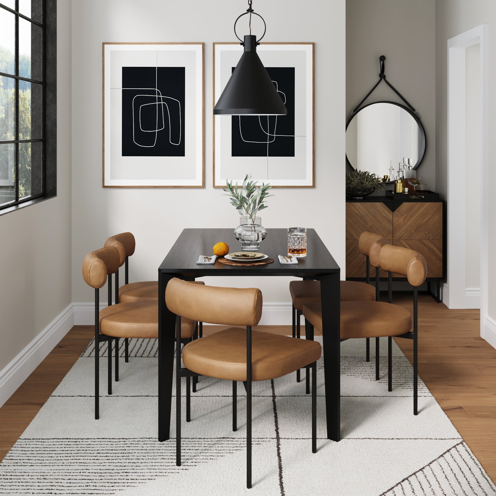 Modern dining room with a black table, four tan leather chairs, black pendant light, abstract art on the wall, a sideboard with a round mirror, and decor accents on a light patterned rug.