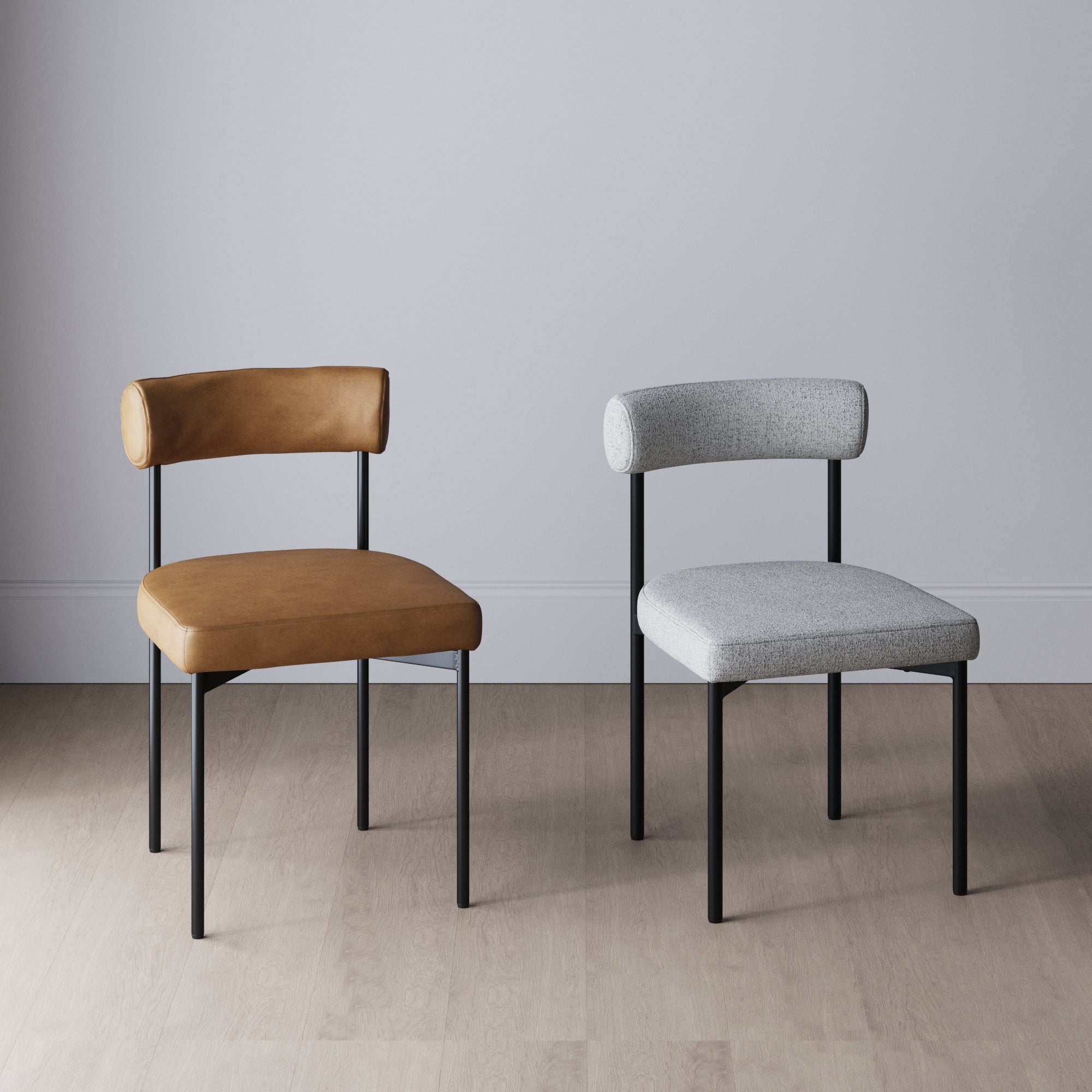 Two modern chairs with black metal legs are shown side by side; the left chair has a tan leather seat and backrest, while the right chair has a light gray fabric seat and backrest. They are placed on a light wood floor.