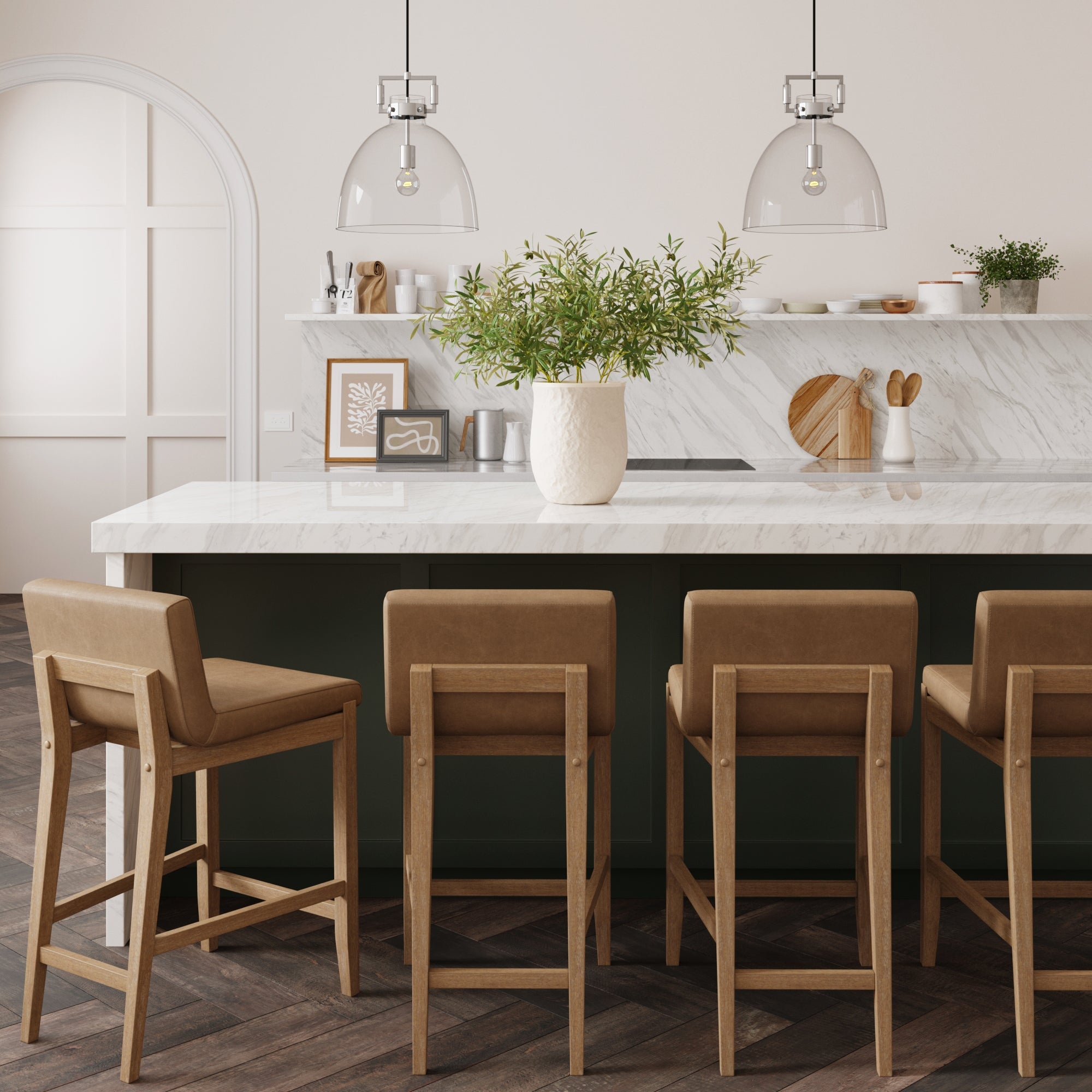 Modern kitchen featuring a marble island, four Nathan James Faux Leather Counter Height Bar Stools in light brown, pendant lights, a large vase with greenery, and minimal decor on white shelves and countertop.