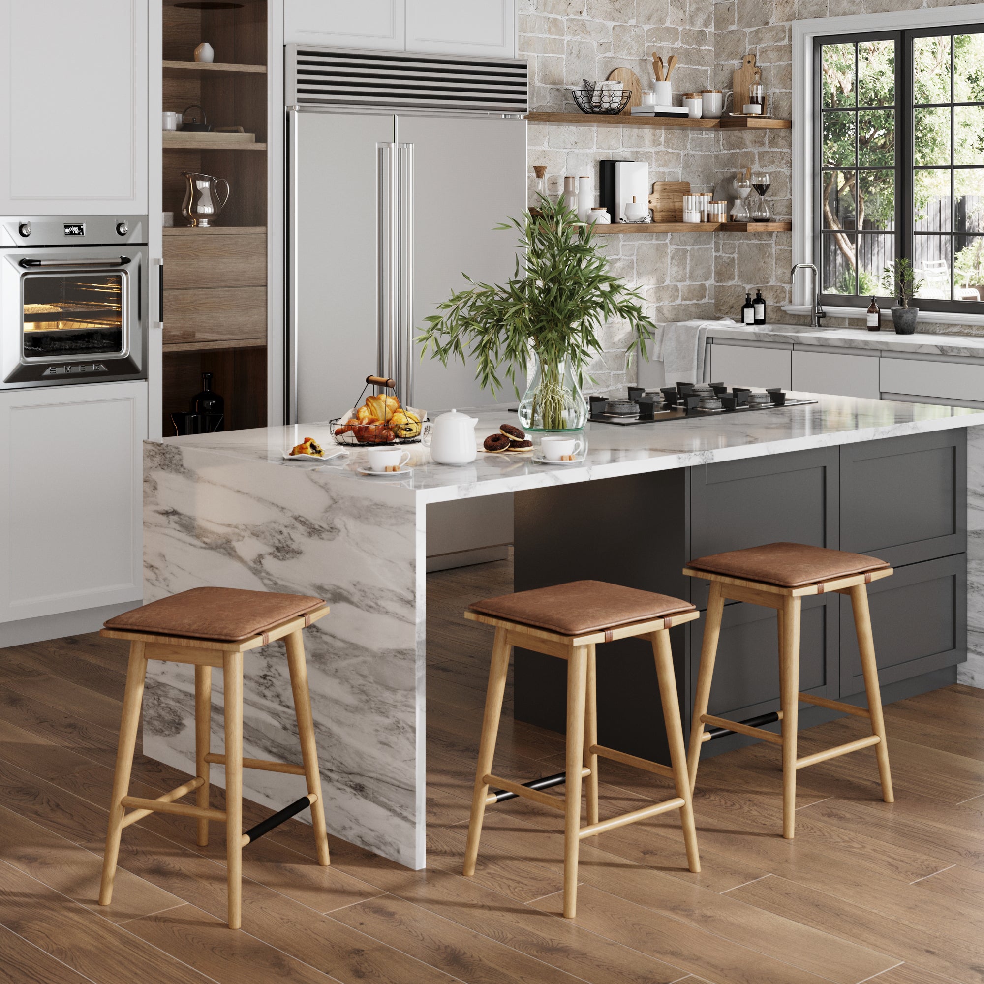 A modern kitchen features a marble island, three Nathan James Cushioned Counter Height Bar Stools in warm pine, built-in appliances, open shelving, and a window with a view of greenery. The island displays a plant, cups, and croissants.