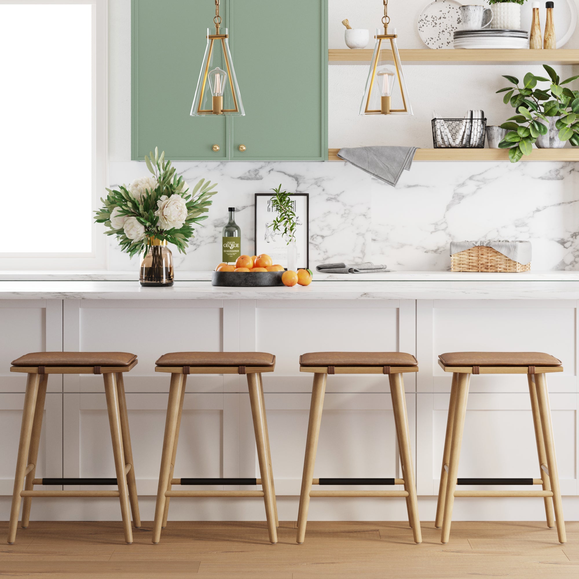 Modern kitchen featuring a white marble island with four Nathan James Cushioned Counter Height Bar Stools in warm pine, green and white cabinets, gold pendant lights, a vase of flowers, a bowl of oranges, and greenery on open shelves.