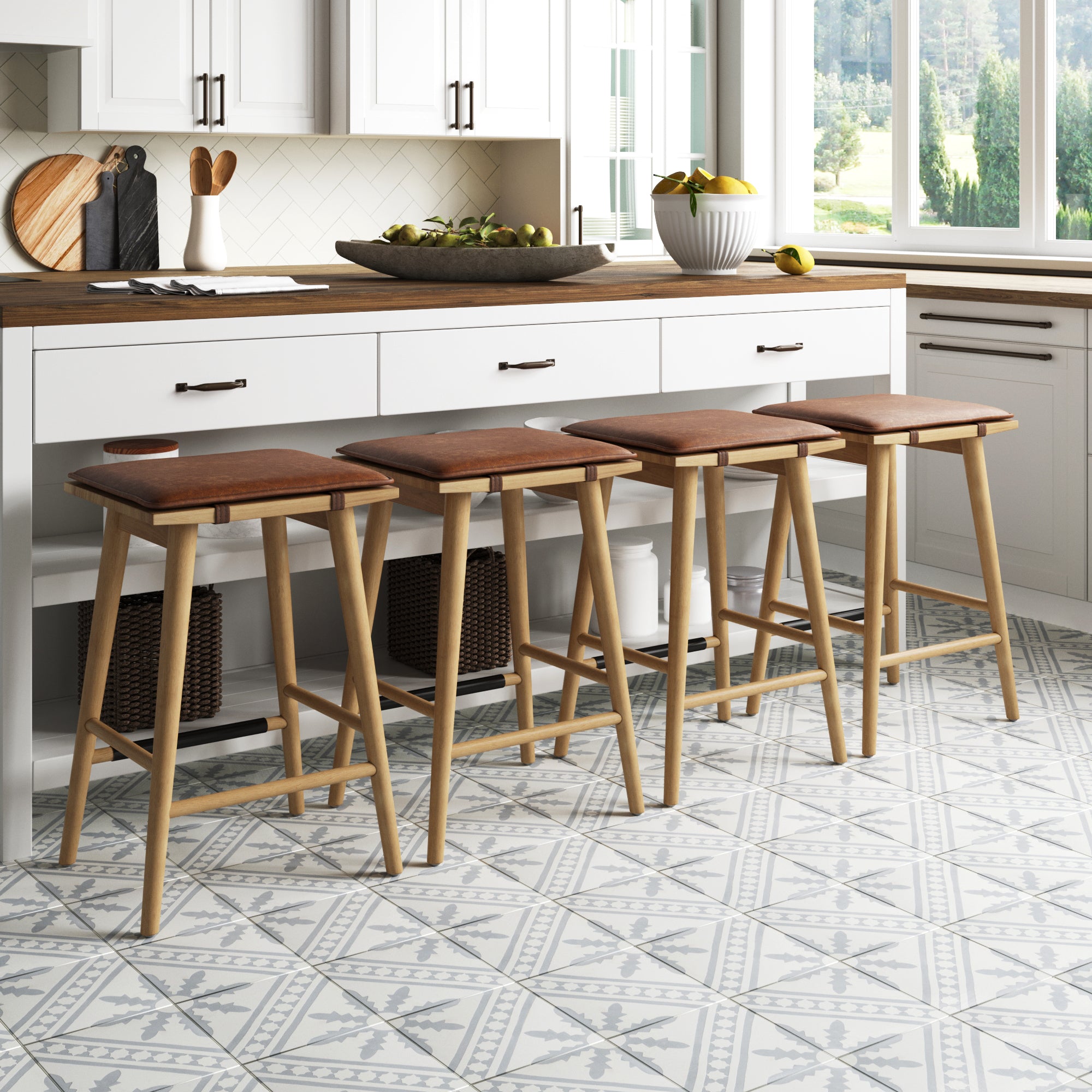 Four wooden barstools with brown seats are lined up under a kitchen island with a wooden countertop. The kitchen features white cabinets, patterned tile flooring, and a bowl of fruit on the counter.