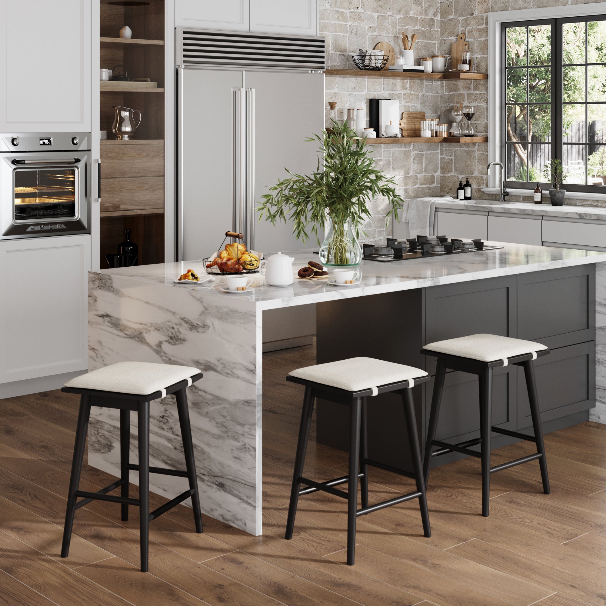 Modern kitchen with a marble island, Nathan James Boucle Counter Height Bar Stools Black (Set of 3), wood flooring, built-in oven, large fridge, and window with greenery view. The island holds breakfast items and a vase with leafy branches.