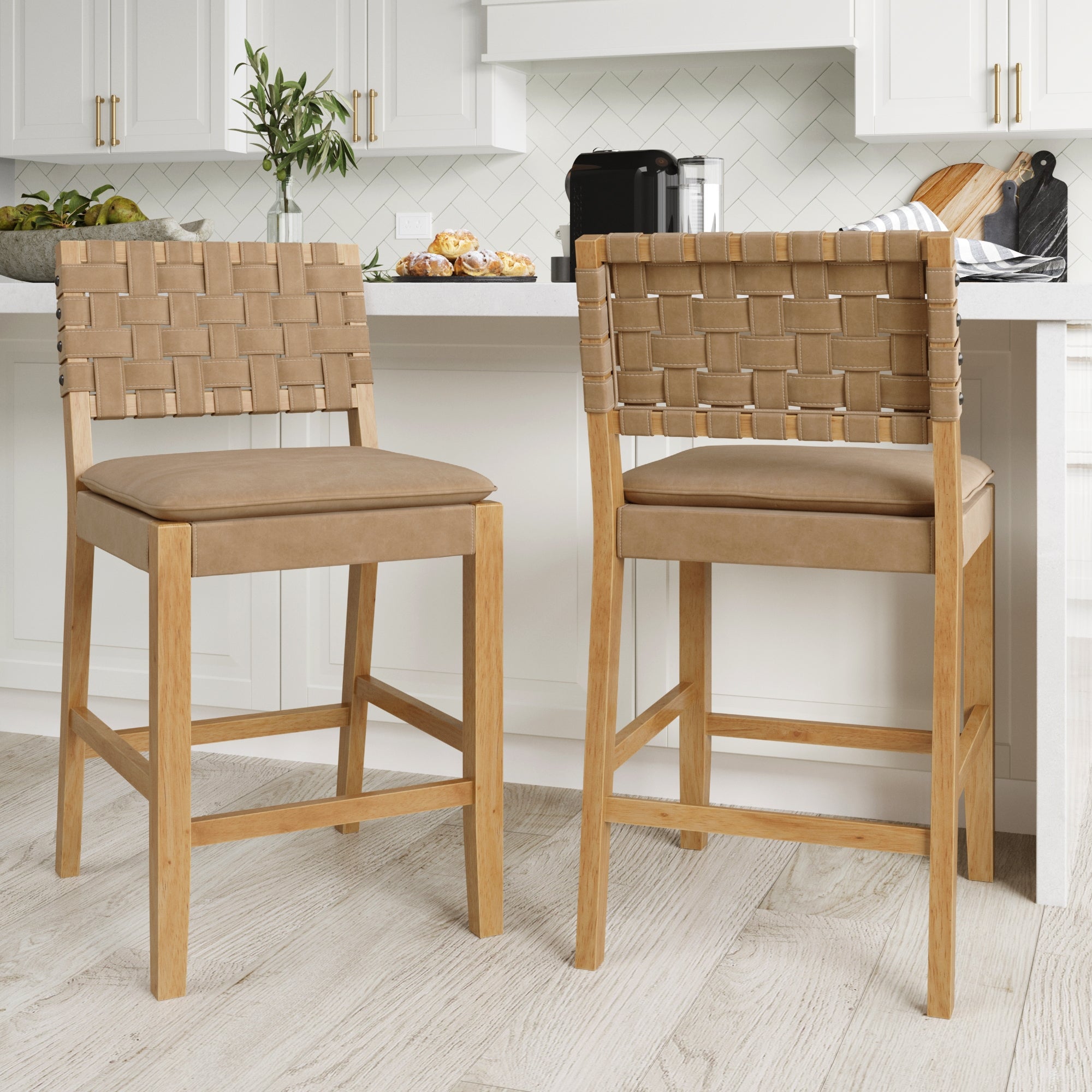 The Nathan James Woven Counter Height Bar Stools Brown (Set of 2) feature solid wood frames and tan woven leather backs with cushioned seats, adding style and comfort to your modern kitchen’s white cabinets and light wood floors.