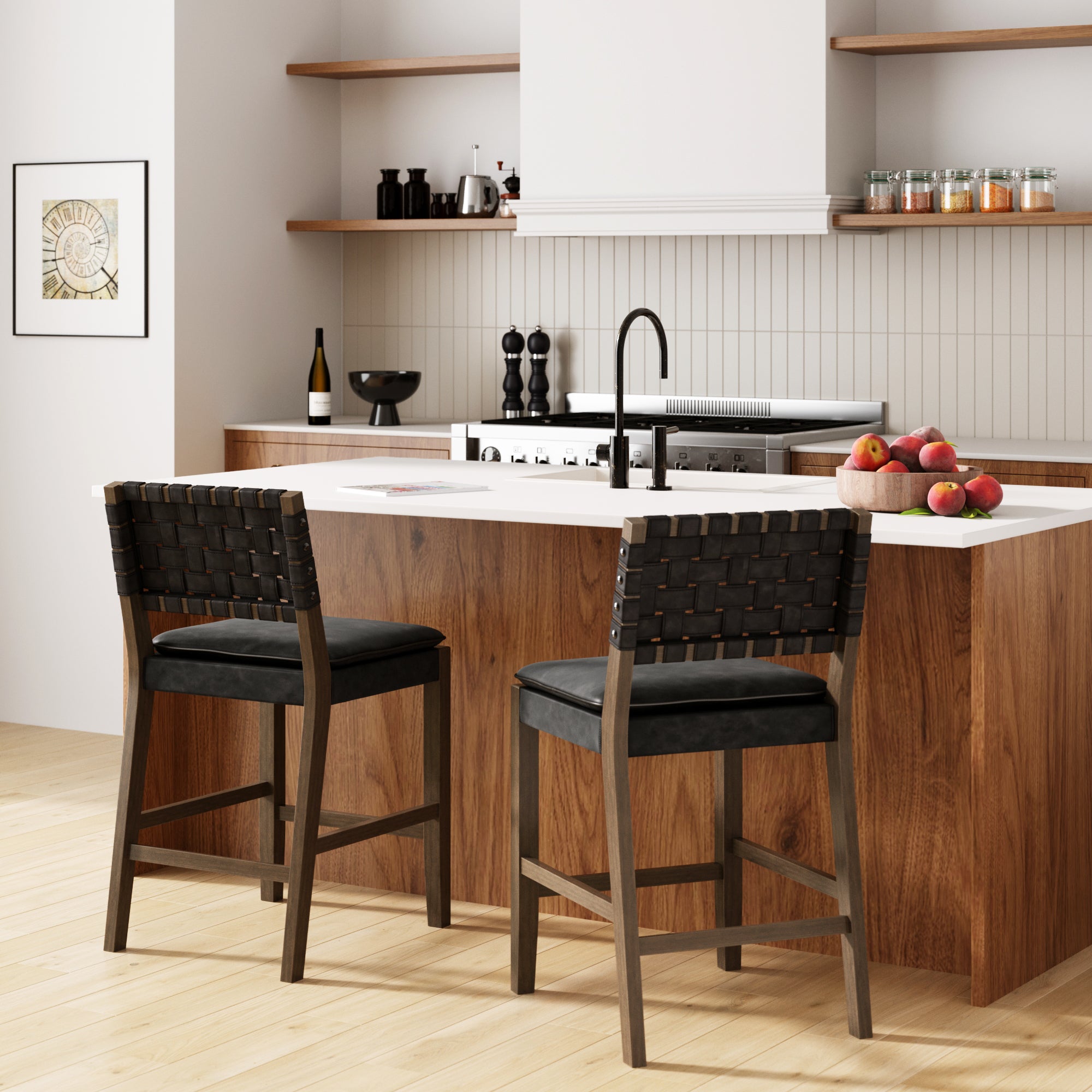 A modern kitchen with a wooden island, two woven black bar stools, open shelves with jars and dishes, a bowl of apples, wine, and a minimalist design. Light wood flooring and neutral colors complete the space.