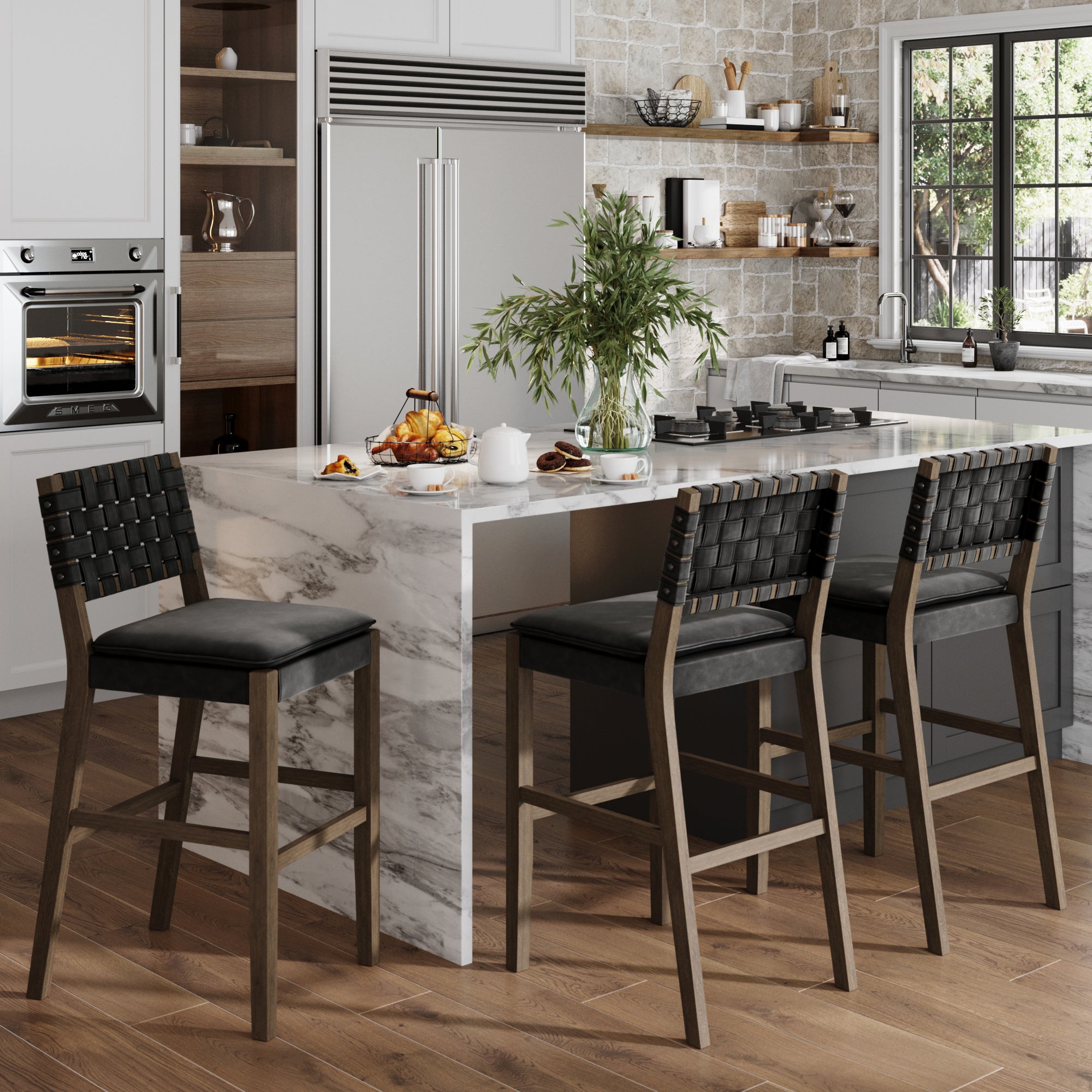 Modern kitchen with a marble island, three Nathan James Faux Leather Woven Bar Stools in black, built-in appliances, large window, solid wood floor, shelves with dishes and decor. The island has plates, cups, and a plant in a vase.